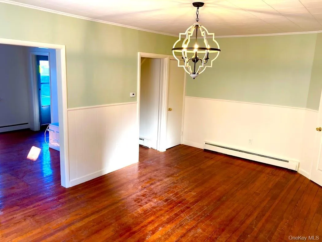 Dining room with hardwood floors, a chandelier, wainscoting and molding Dining room with hardwood floors, a chandelier, wainscoting and molding
