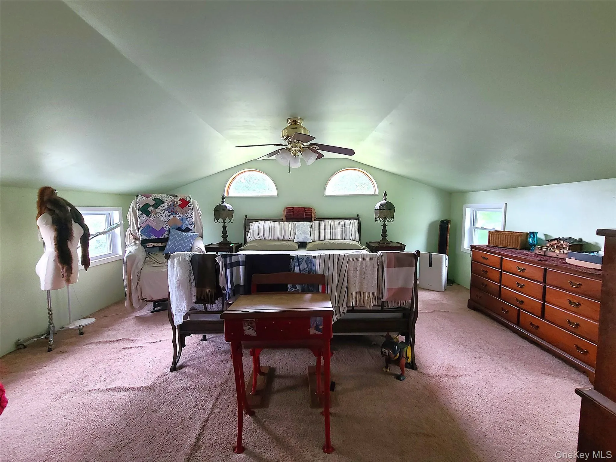 Carpeted bedroom with vaulted ceiling, multiple windows, and ceiling fan Carpeted bedroom with vaulted ceiling, multiple windows, and ceiling fan