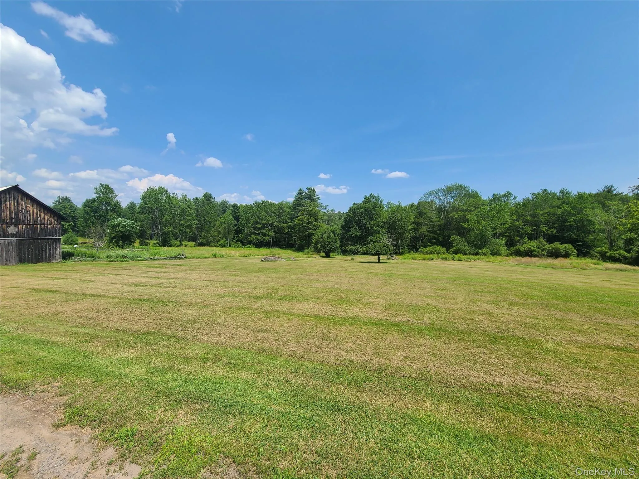 View of green lawn featuring a barn, an outdoor structure, a view of rural / pastoral area, and a wooded view View of green lawn featuring a barn, an outdoor structure, a view of rural / pastoral area, and a wooded view