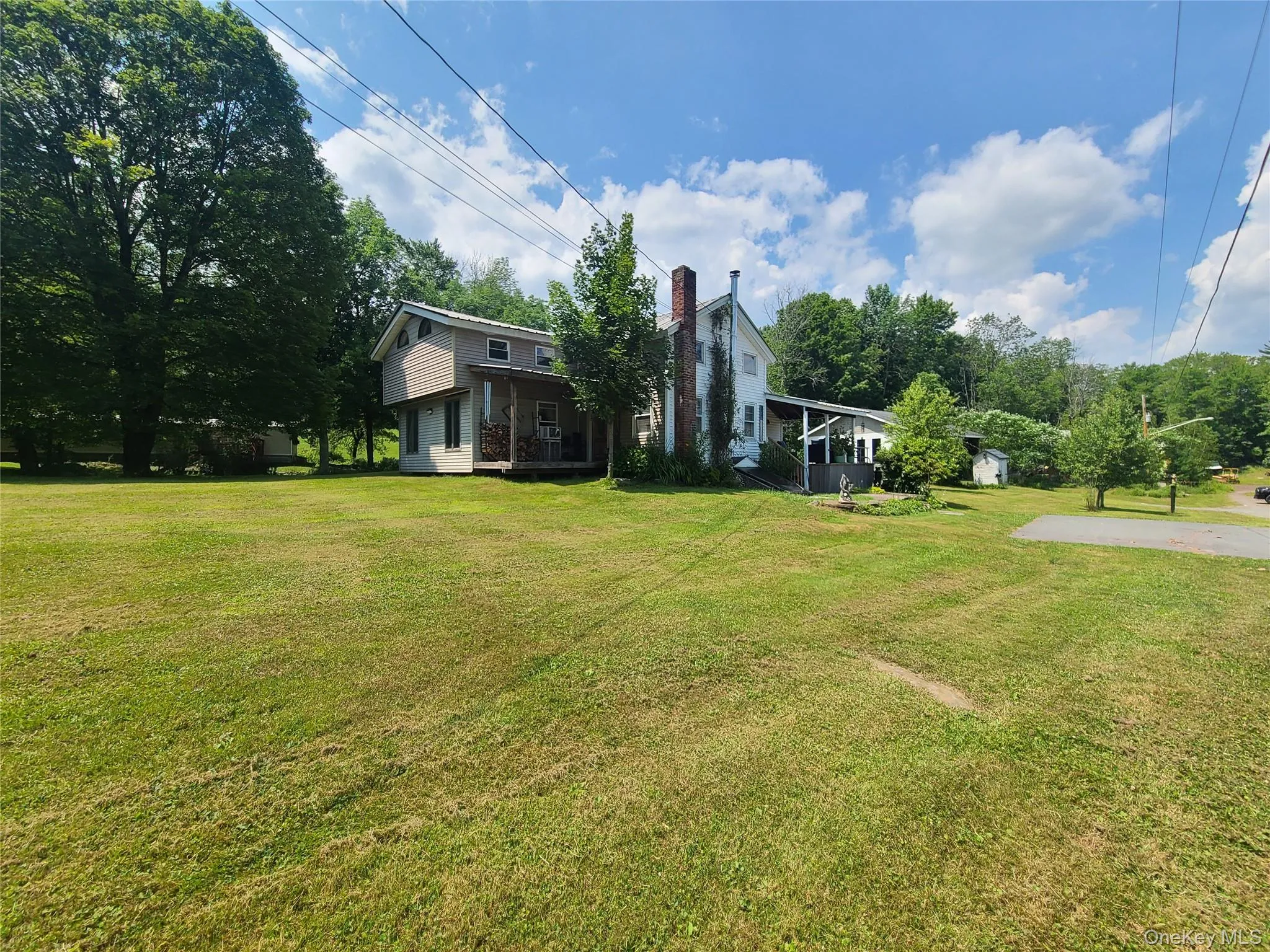 View of green lawn featuring a sunroom and view of wooded area View of green lawn featuring a sunroom and view of wooded area