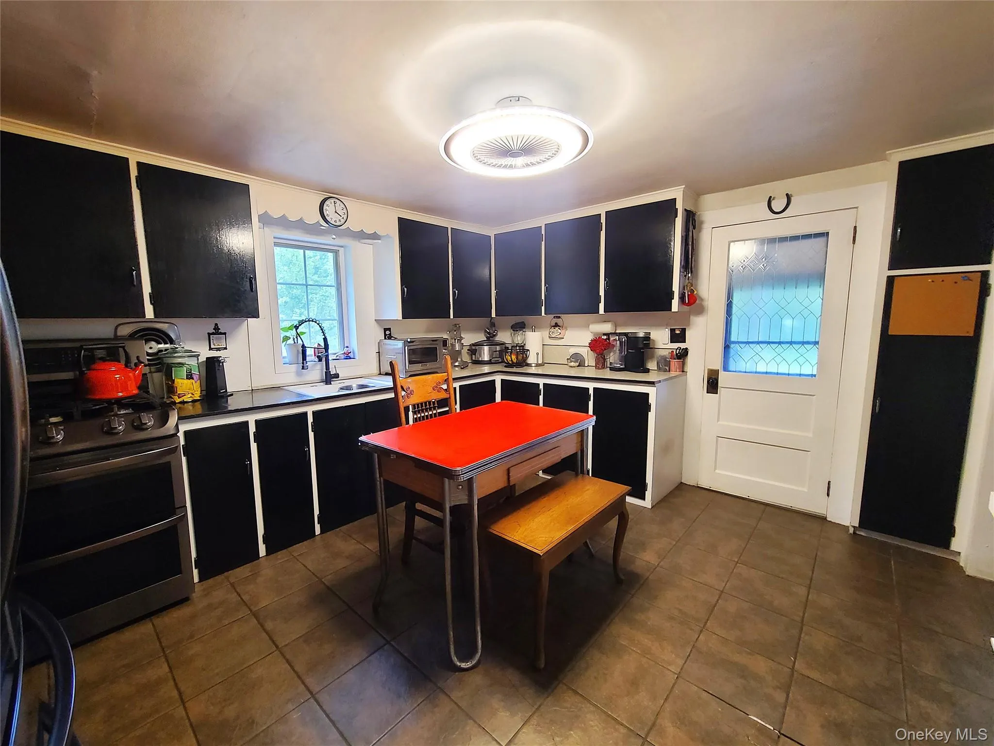 Kitchen with dark cabinets, dark tile patterned flooring, range with two ovens, and freestanding refrigerator Kitchen with dark cabinets, dark tile patterned flooring, range with two ovens, and freestanding refrigerator