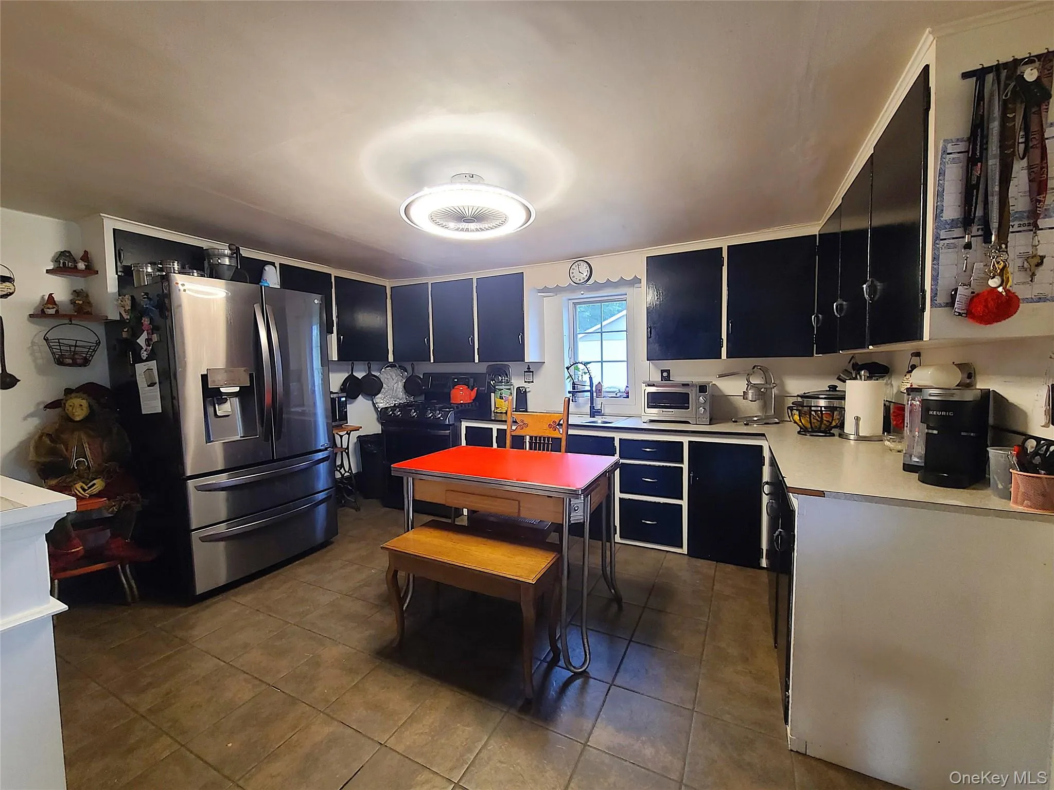 Kitchen with stainless steel refrigerator with ice dispenser, dark tile patterned flooring, light countertops, and dark cabinetry Kitchen with stainless steel refrigerator with ice dispenser, dark tile patterned flooring, light countertops, and dark cabinetry