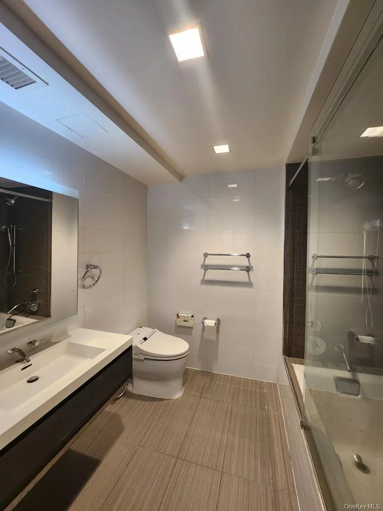 Full bath with tile walls, vanity, and a shower Full bath with tile walls, vanity, and a shower