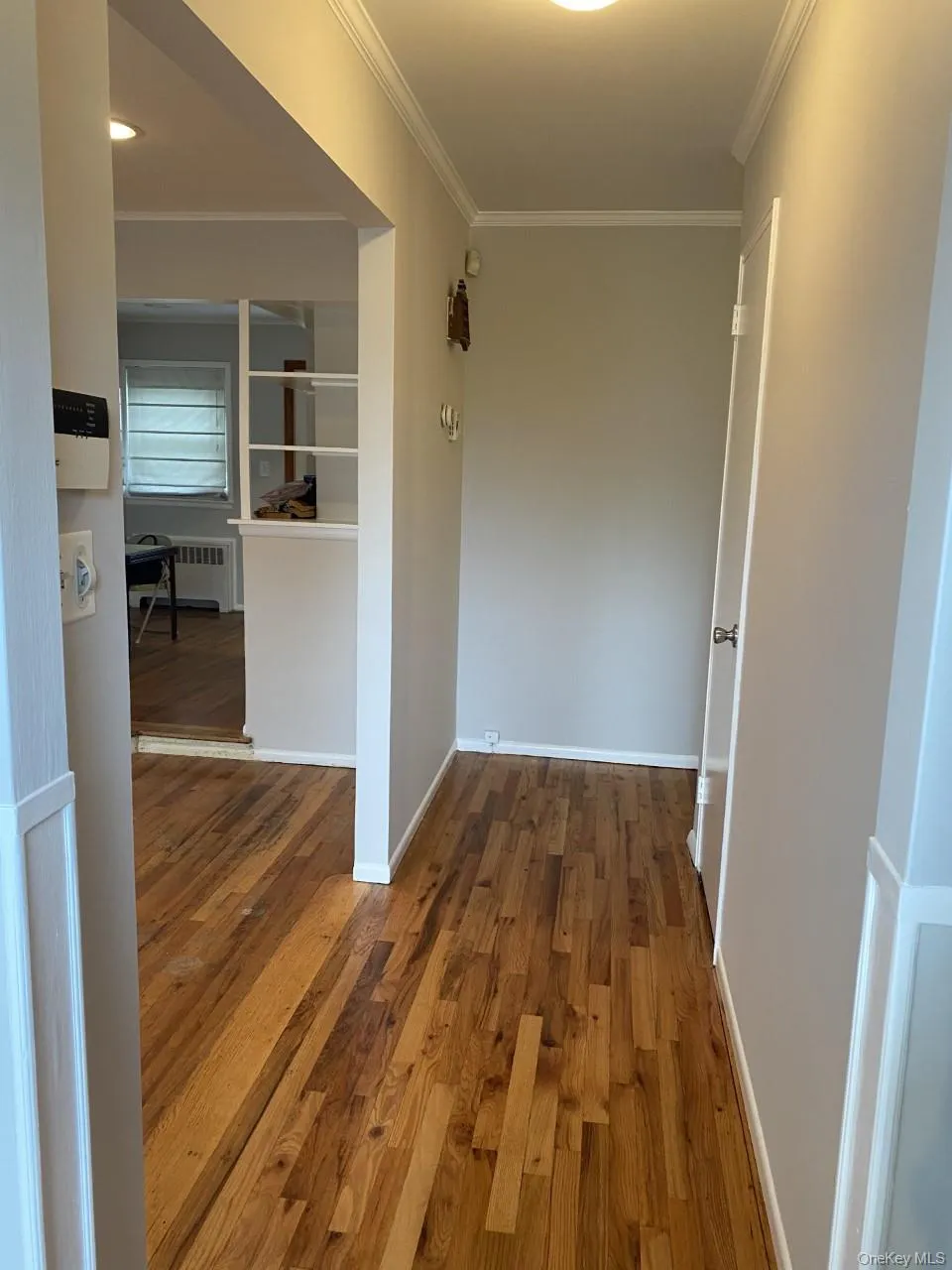 Hall with wood finished floors, crown molding, and radiator heating unit Hall with wood finished floors, crown molding, and radiator heating unit