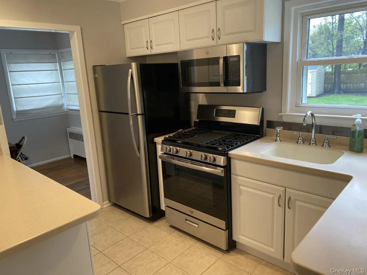 Kitchen with some stainless steel appliances, white cabinetry, light countertops, and radiator Kitchen with some stainless steel appliances, white cabinetry, light countertops, and radiator