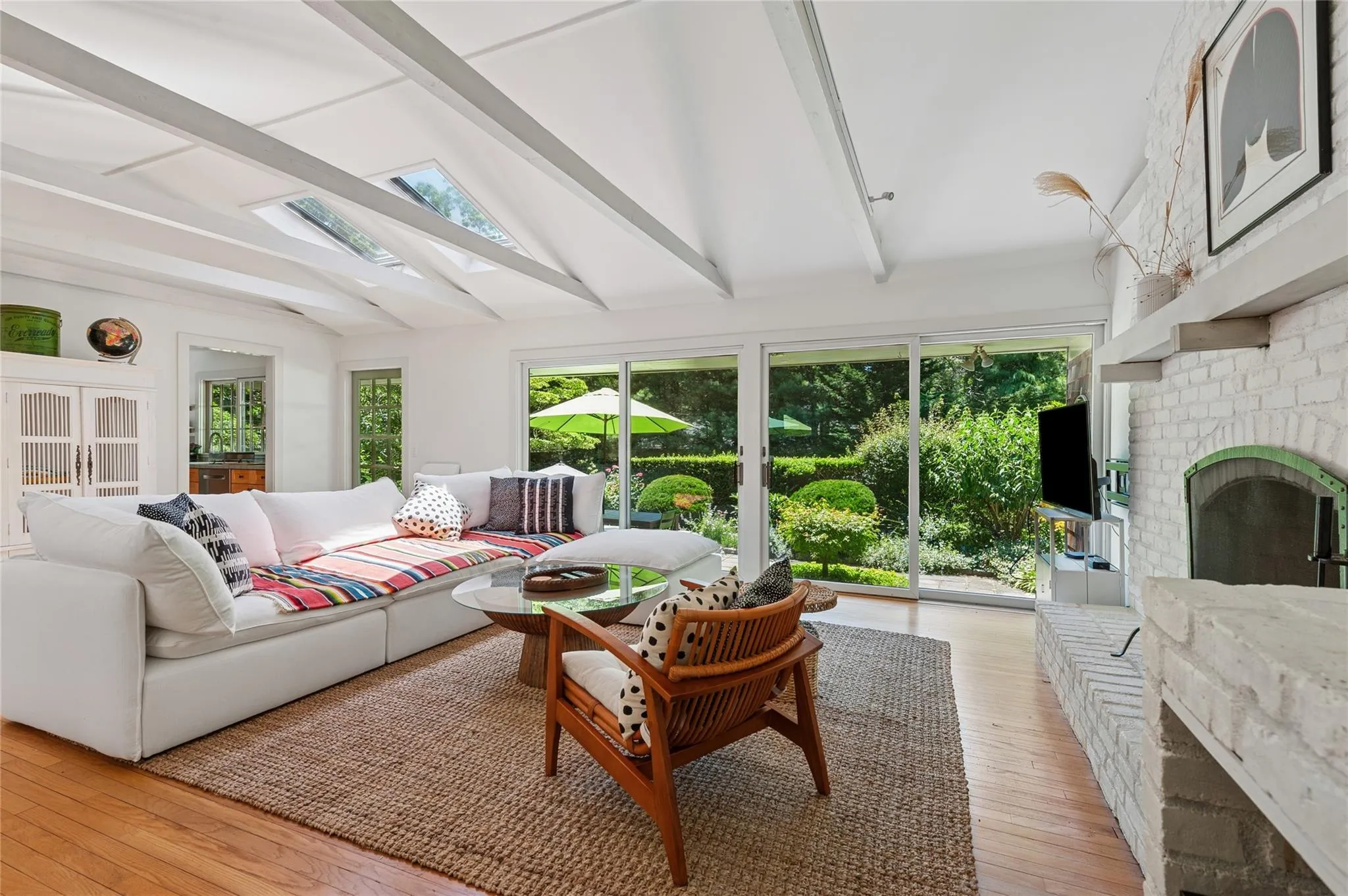 Living room with a skylight, light wood-style floors, and a brick fireplace Living room with a skylight, light wood-style floors, and a brick fireplace