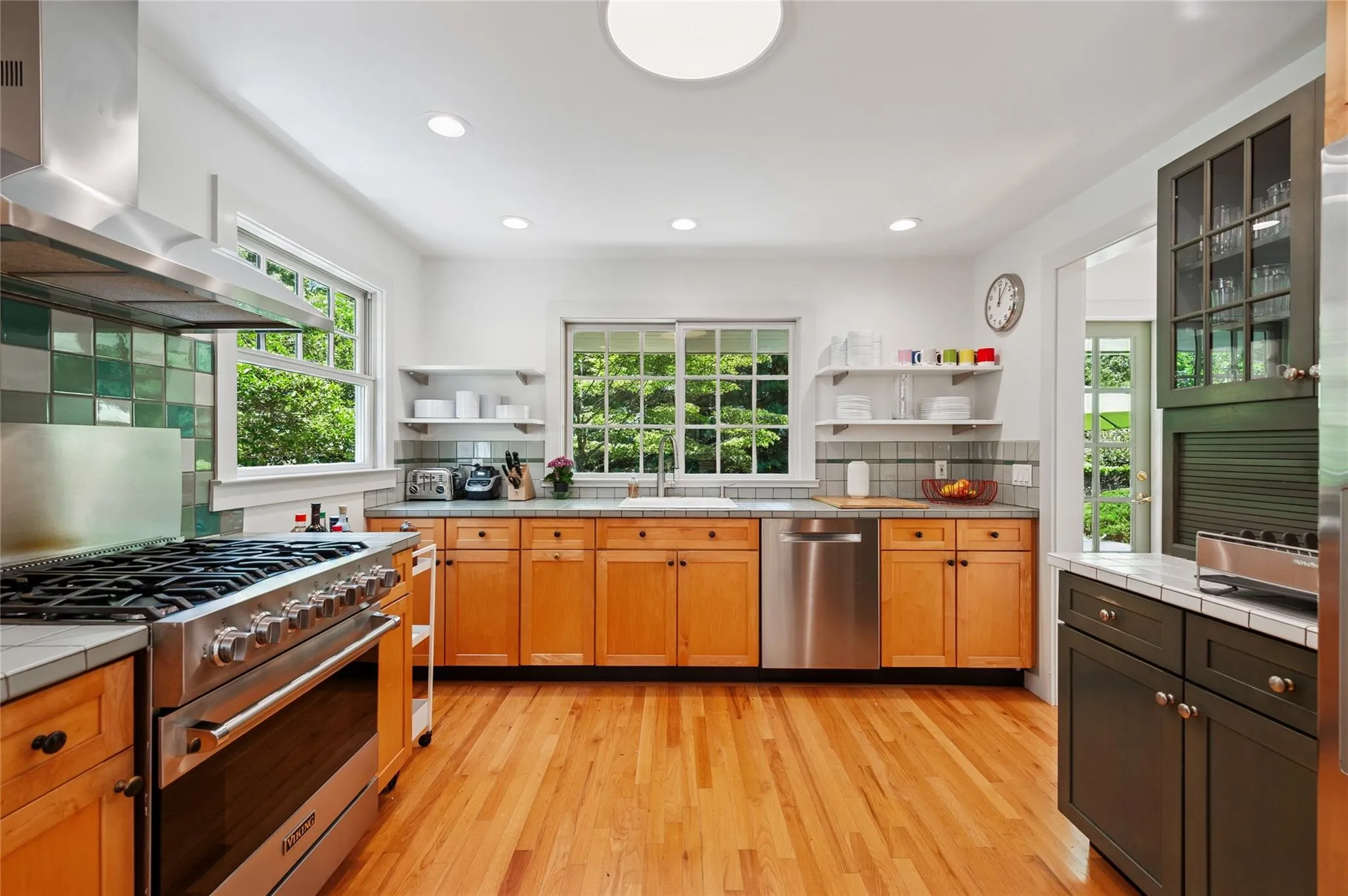 Kitchen with open shelves, tile counters, appliances with stainless steel finishes, plenty of natural light, and recessed lighting Kitchen with open shelves, tile counters, appliances with stainless steel finishes, plenty of natural light, and recessed lighting