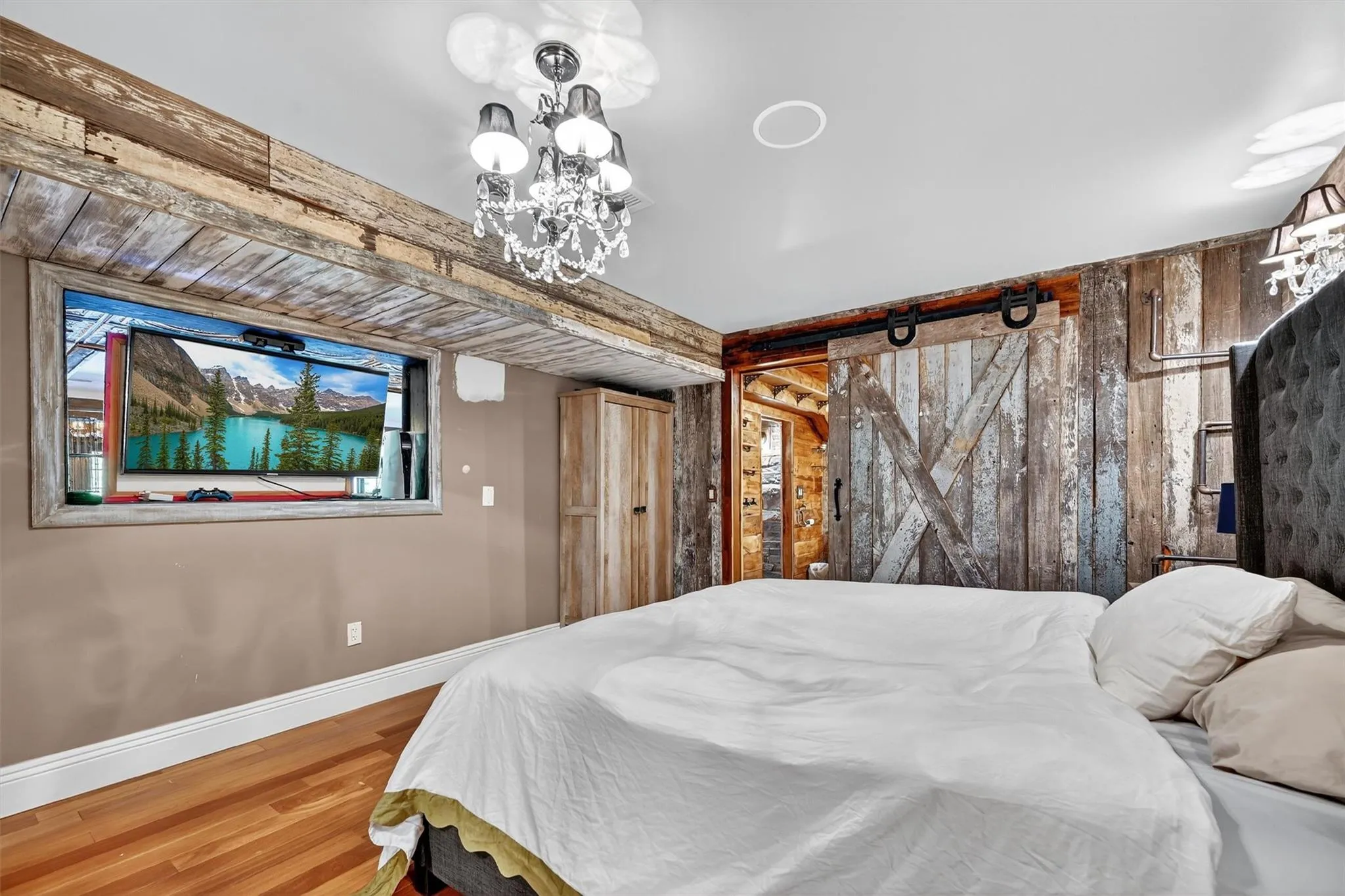 Bedroom featuring wood finished floors, wood walls, and a chandelier Bedroom featuring wood finished floors, wood walls, and a chandelier