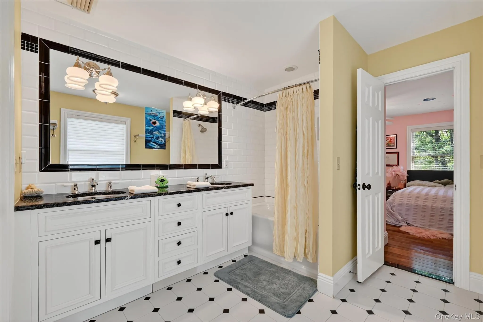 Ensuite bathroom featuring shower / bathtub combination with curtain, double vanity, and a chandelier Ensuite bathroom featuring shower / bathtub combination with curtain, double vanity, and a chandelier