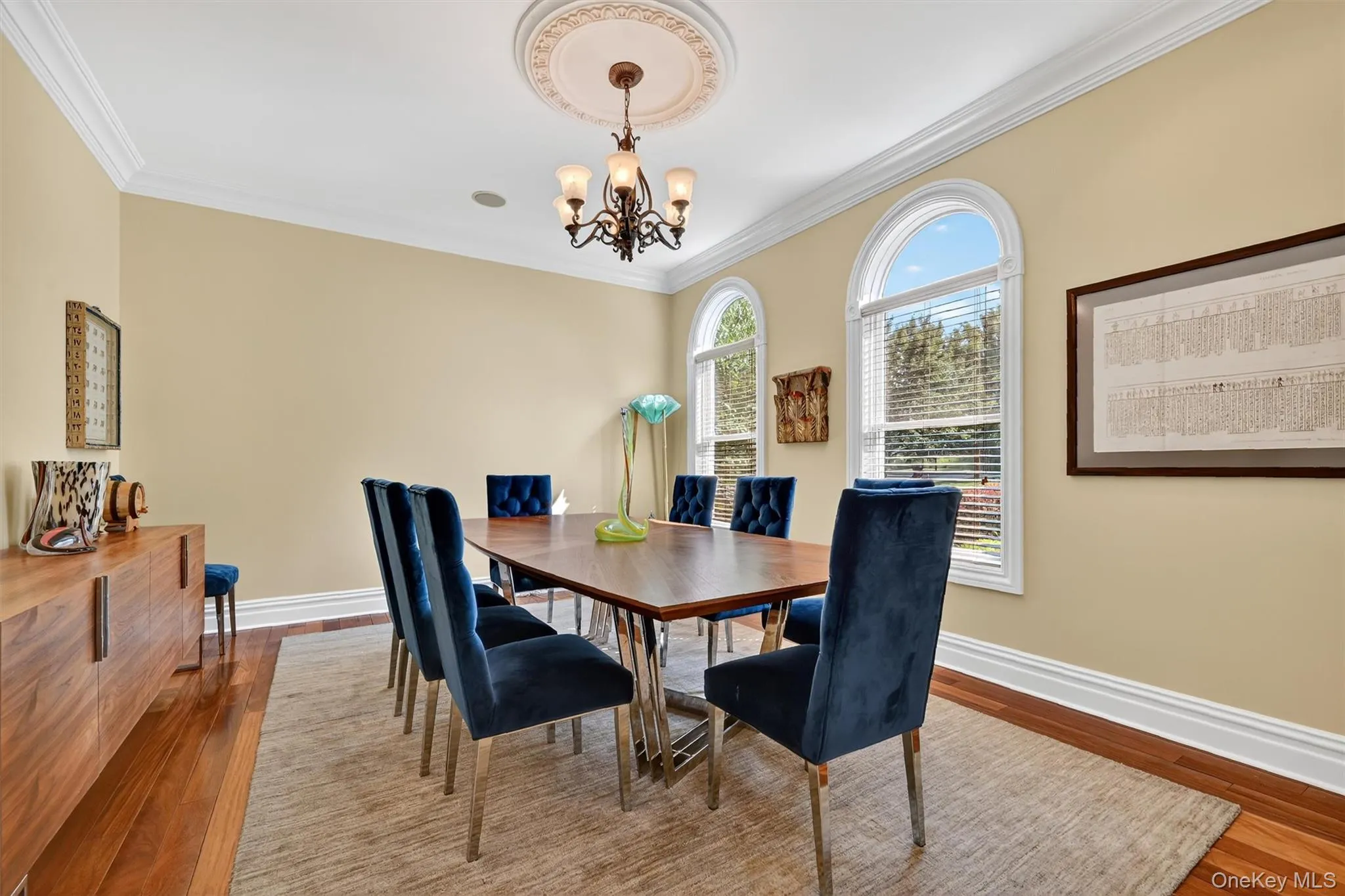 Dining space featuring wood finished floors, a chandelier, and crown molding Dining space featuring wood finished floors, a chandelier, and crown molding
