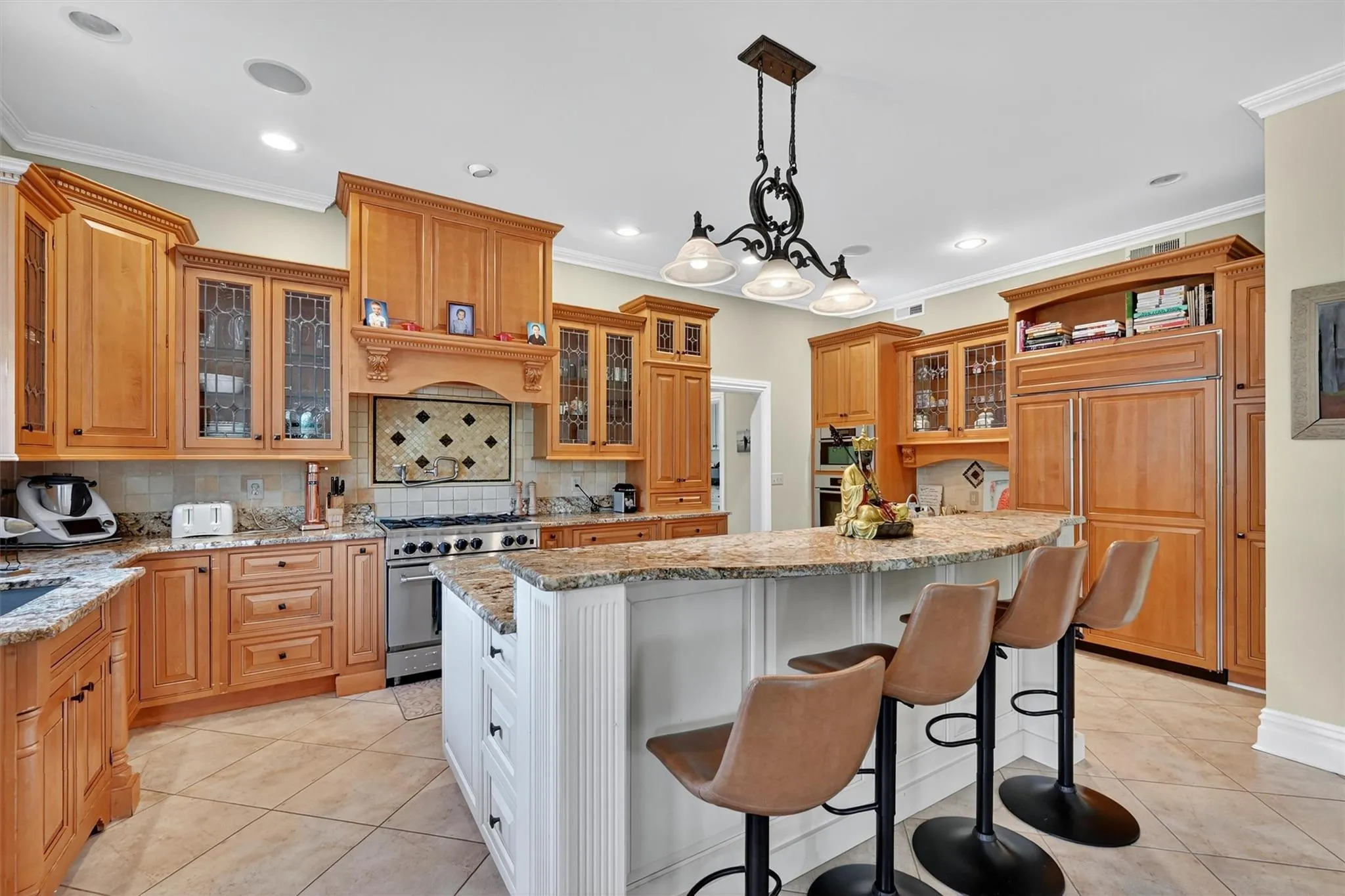 Kitchen featuring a kitchen island, a breakfast bar area, light tile patterned floors, high quality appliances, and decorative backsplash Kitchen featuring a kitchen island, a breakfast bar area, light tile patterned floors, high quality appliances, and decorative backsplash