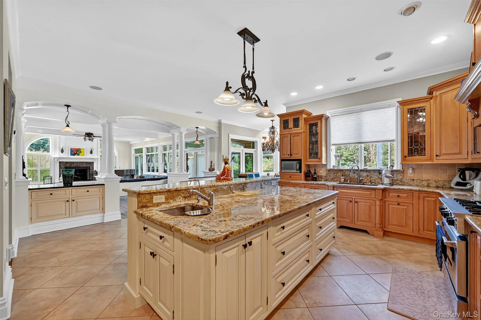 Kitchen featuring ornate columns, an island with sink, arched walkways, high end stainless steel range, and ornamental molding Kitchen featuring ornate columns, an island with sink, arched walkways, high end stainless steel range, and ornamental molding