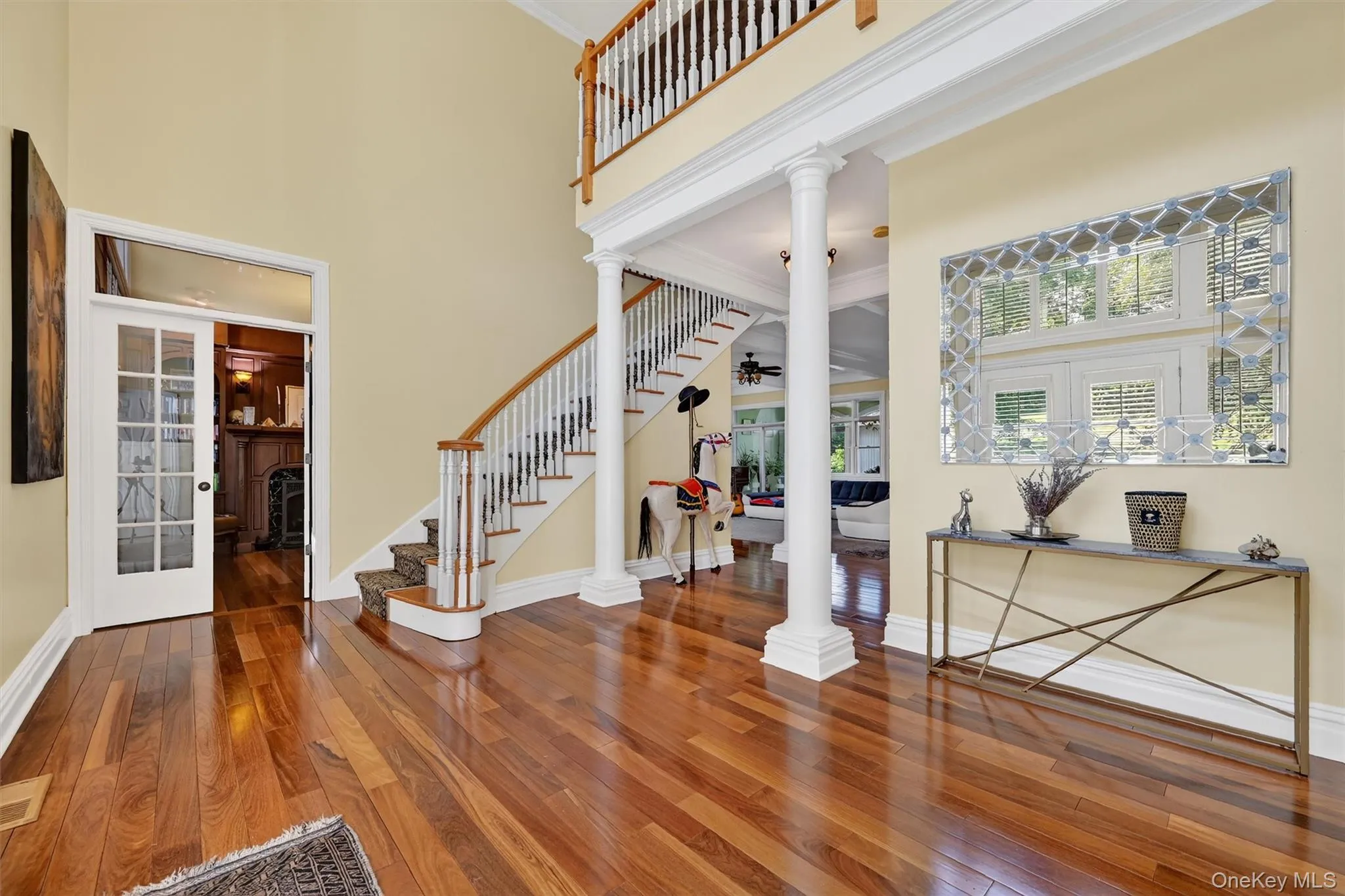 Entryway with a high ceiling, decorative columns, stairs, hardwood / wood-style floors, and ornamental molding Entryway with a high ceiling, decorative columns, stairs, hardwood / wood-style floors, and ornamental molding