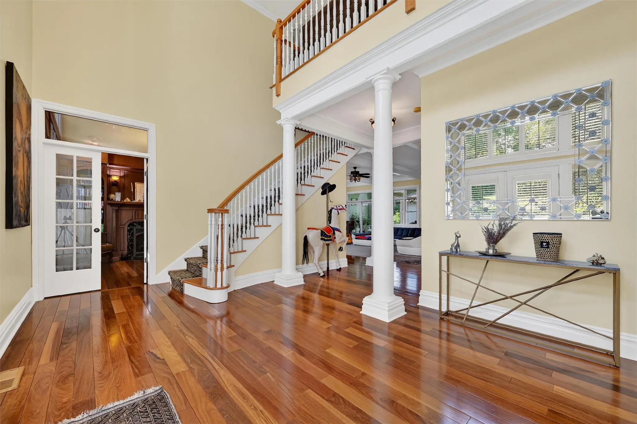 Entryway with a high ceiling, decorative columns, stairs, hardwood / wood-style floors, and ornamental molding Entryway with a high ceiling, decorative columns, stairs, hardwood / wood-style floors, and ornamental molding