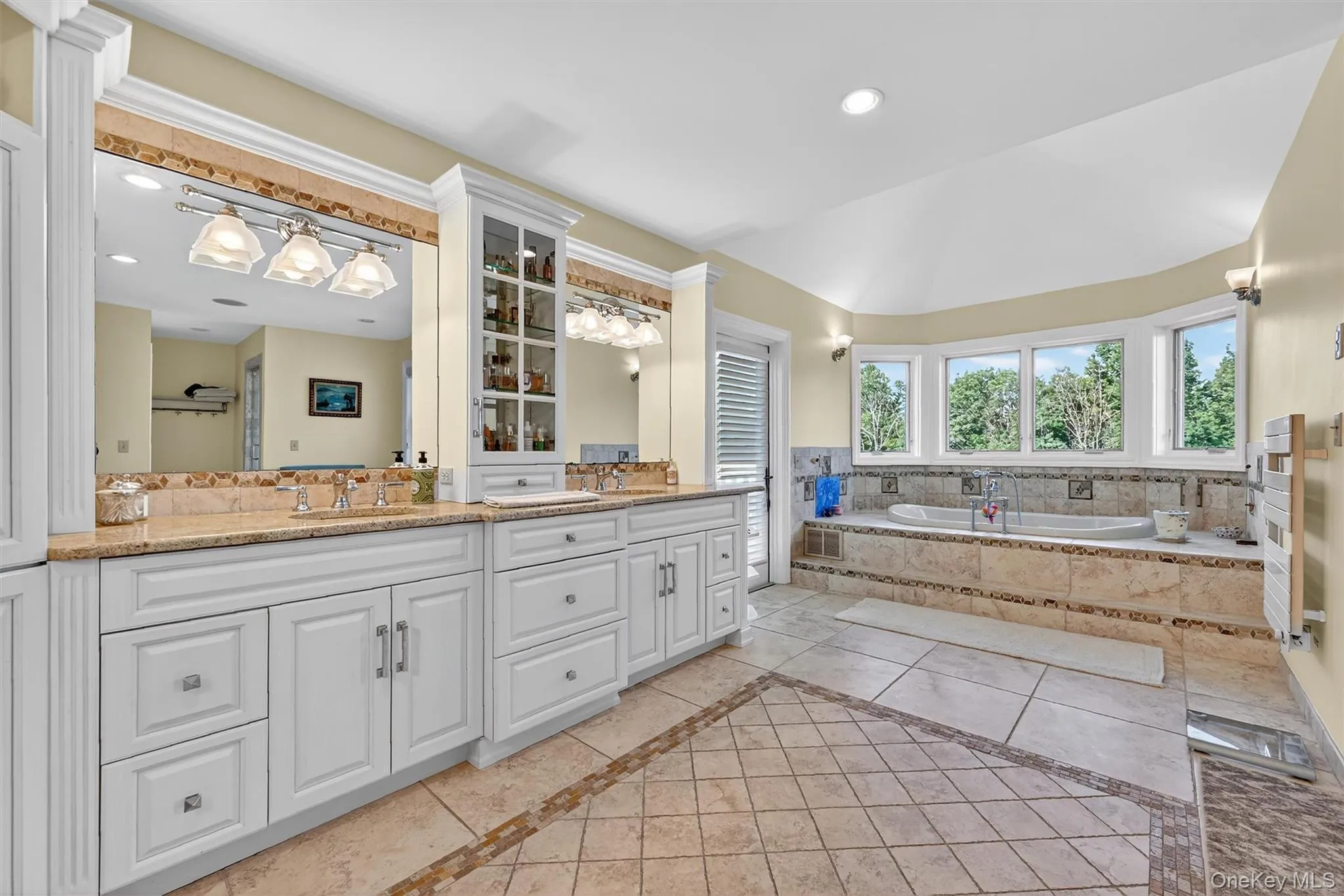 Full bathroom featuring inlaid floor details, double vanity, a garden tub, radiator, and recessed lighting Full bathroom featuring inlaid floor details, double vanity, a garden tub, radiator, and recessed lighting