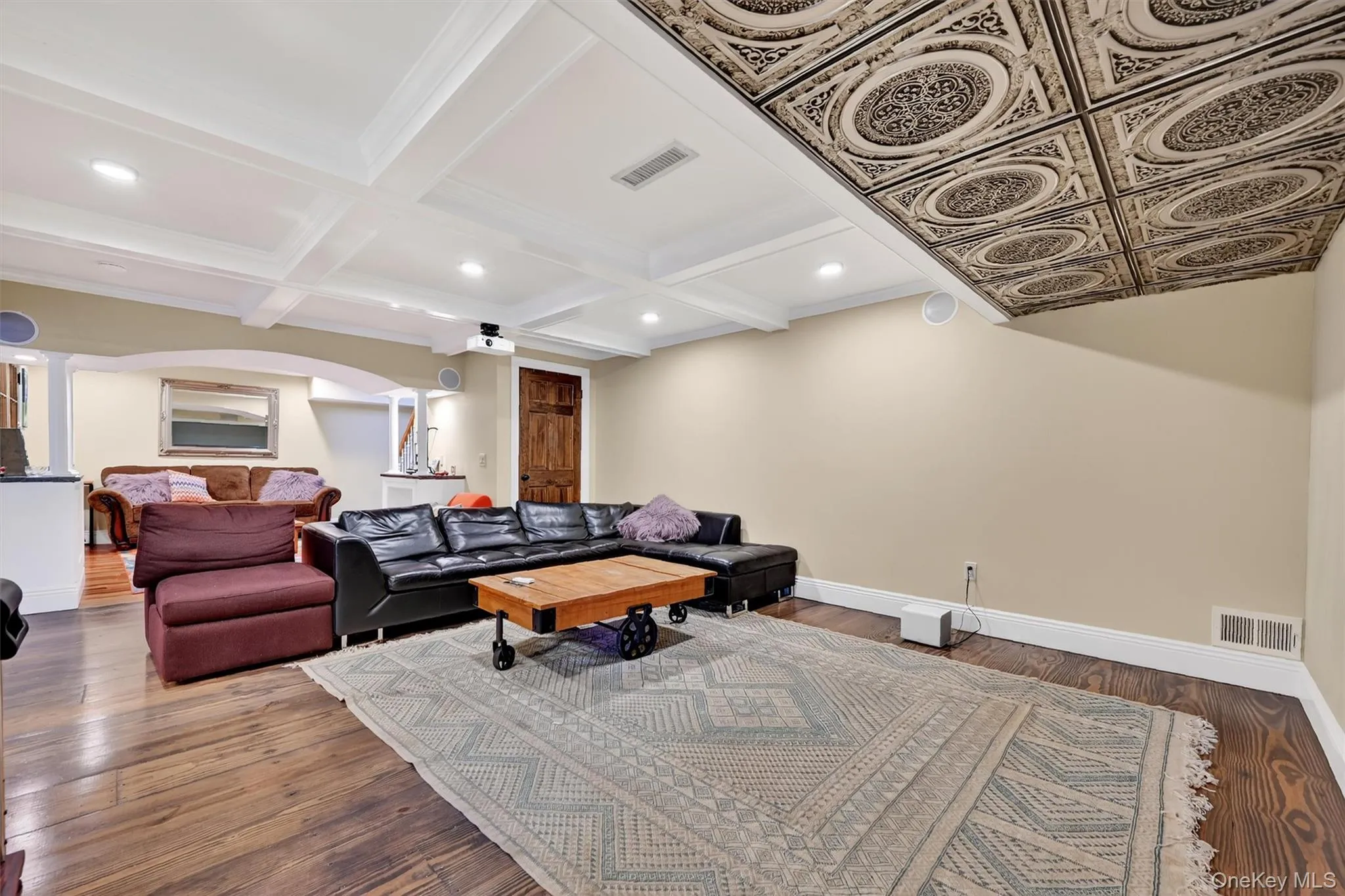 Living room with beam ceiling, wood finished floors, coffered ceiling, arched walkways, and recessed lighting Living room with beam ceiling, wood finished floors, coffered ceiling, arched walkways, and recessed lighting