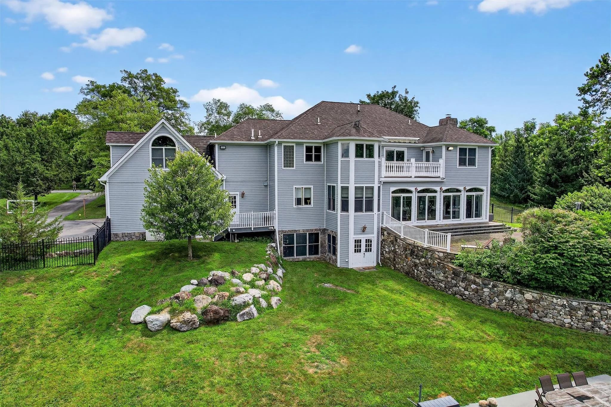 Rear view of property with a chimney, a balcony, a sunroom, and roof with shingles Rear view of property with a chimney, a balcony, a sunroom, and roof with shingles