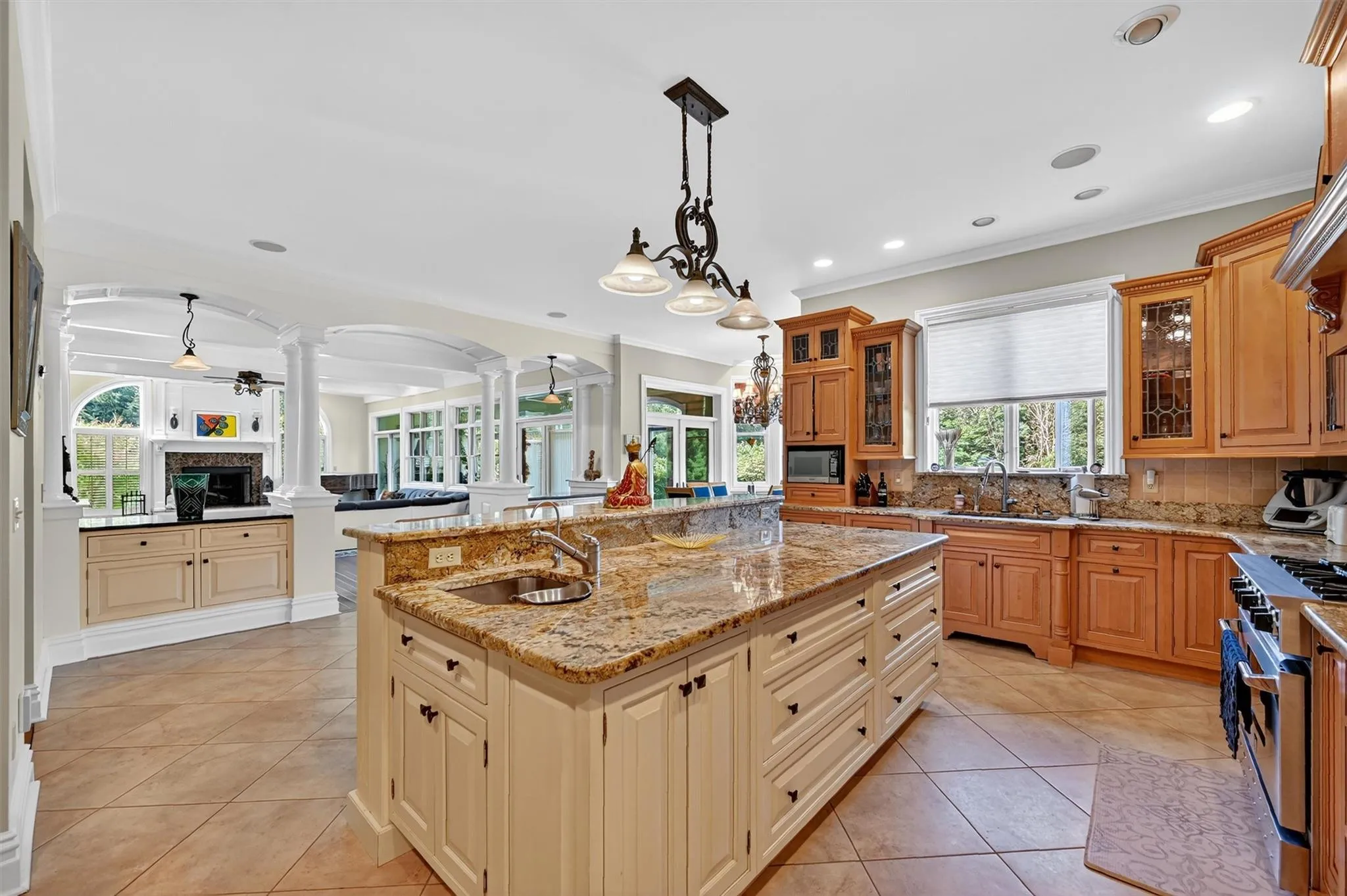 Kitchen featuring ornate columns, an island with sink, arched walkways, high end stainless steel range, and ornamental molding Kitchen featuring ornate columns, an island with sink, arched walkways, high end stainless steel range, and ornamental molding