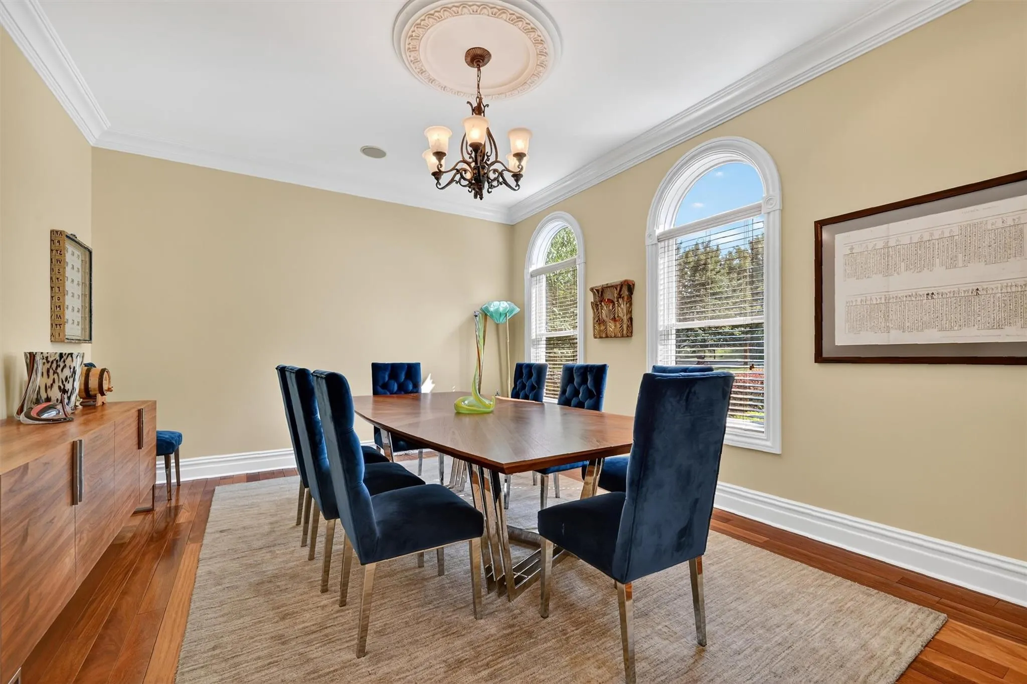 Dining space featuring wood finished floors, a chandelier, and crown molding Dining space featuring wood finished floors, a chandelier, and crown molding