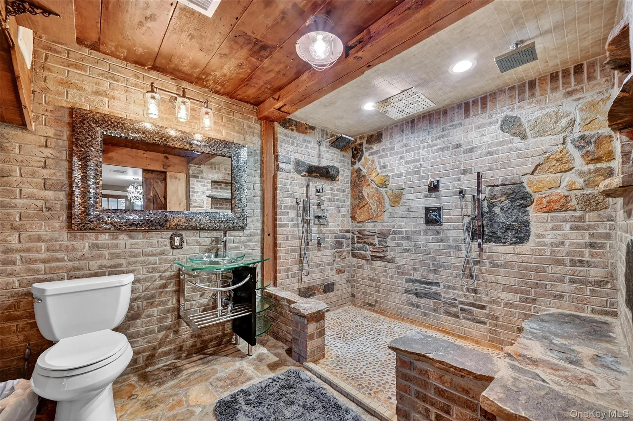 Bathroom with brick wall, wooden ceiling, a tile shower, and stone finish floors Bathroom with brick wall, wooden ceiling, a tile shower, and stone finish floors