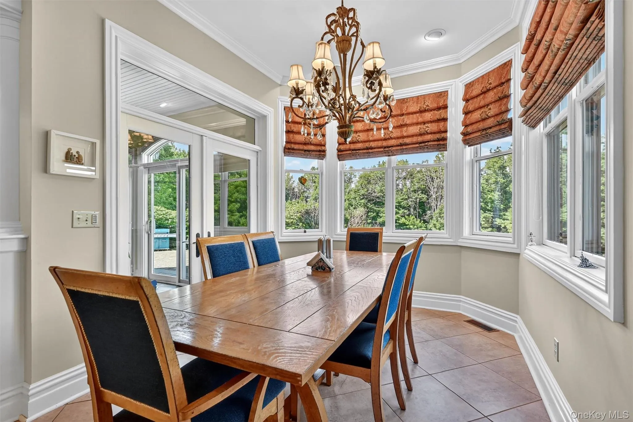Tiled dining space with plenty of natural light, a chandelier, and ornamental molding Tiled dining space with plenty of natural light, a chandelier, and ornamental molding