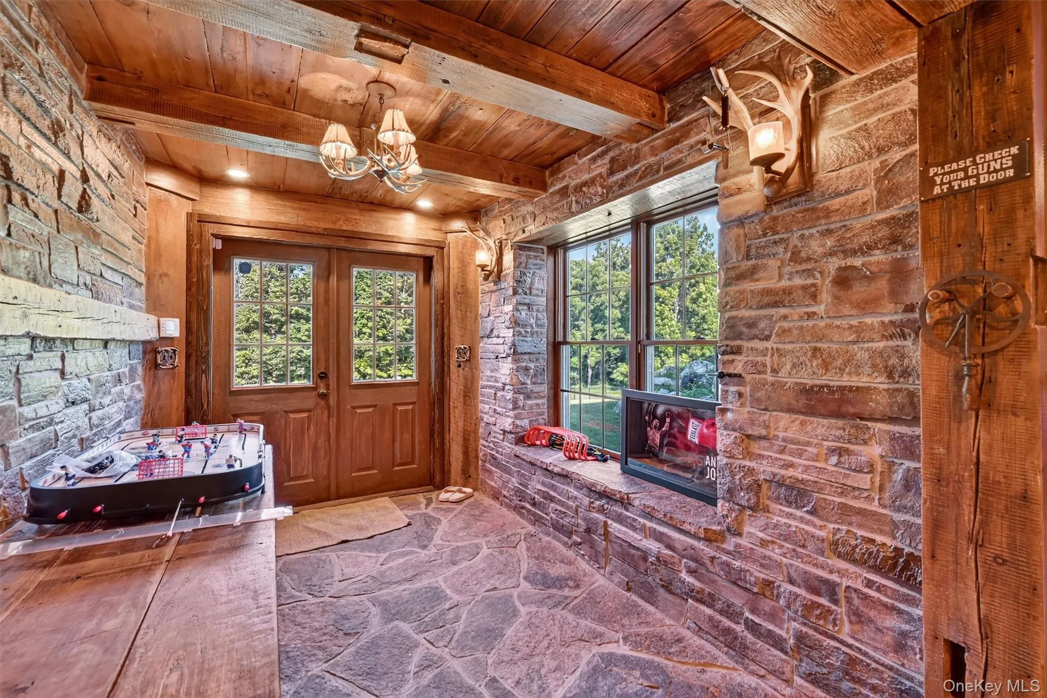Entrance foyer with a wood ceiling with exposed beams, stone floors, plenty of natural light, and a chandelier Entrance foyer with a wood ceiling with exposed beams, stone floors, plenty of natural light, and a chandelier