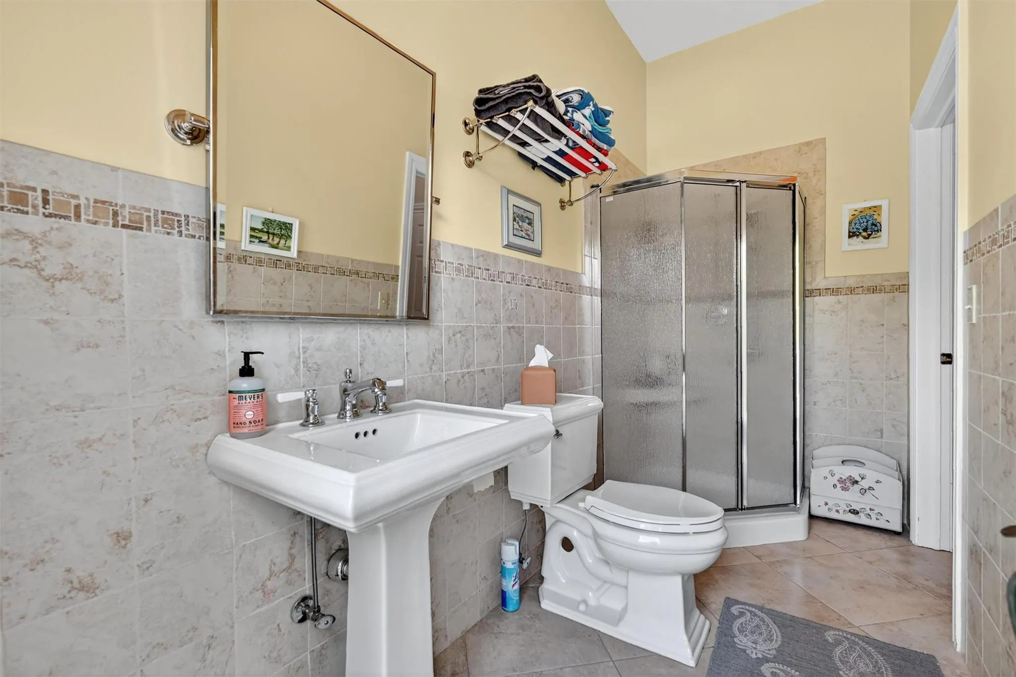 Bathroom on main floor with outside access for pool use. featuring tile walls, a shower stall, tile patterned floors, and a wainscoted wall Bathroom on main floor with outside access for pool use. featuring tile walls, a shower stall, tile patterned floors, and a wainscoted wall