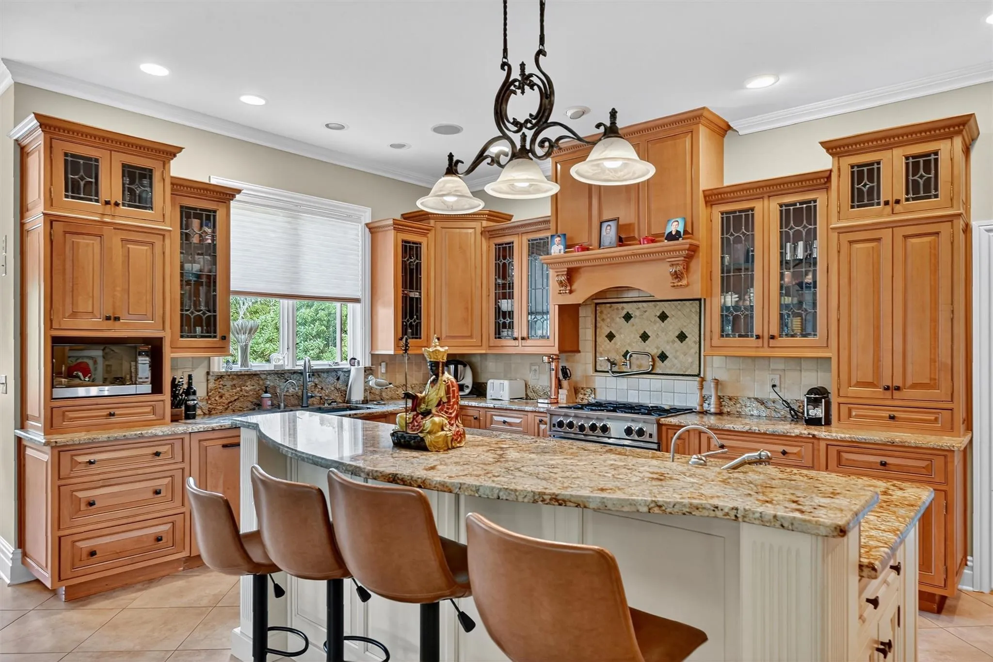 Kitchen featuring a kitchen island, light tile patterned floors, recessed lighting, a kitchen breakfast bar, and ornamental molding Kitchen featuring a kitchen island, light tile patterned floors, recessed lighting, a kitchen breakfast bar, and ornamental molding