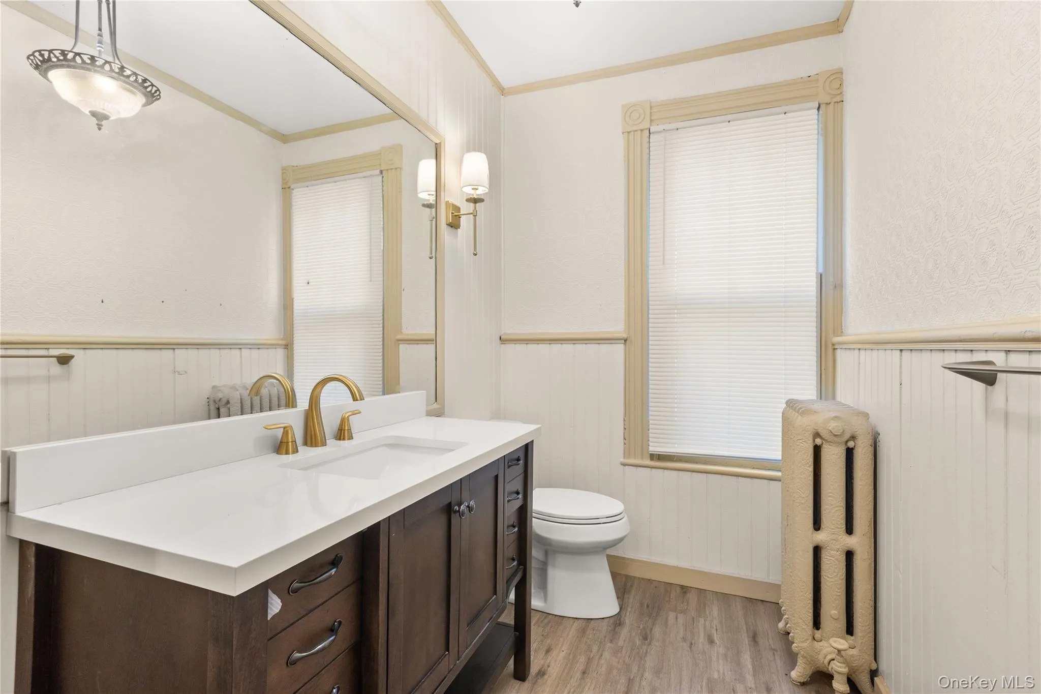 Half bath with light wood-style flooring, vanity, radiator heating unit, and ornamental molding Half bath with light wood-style flooring, vanity, radiator heating unit, and ornamental molding