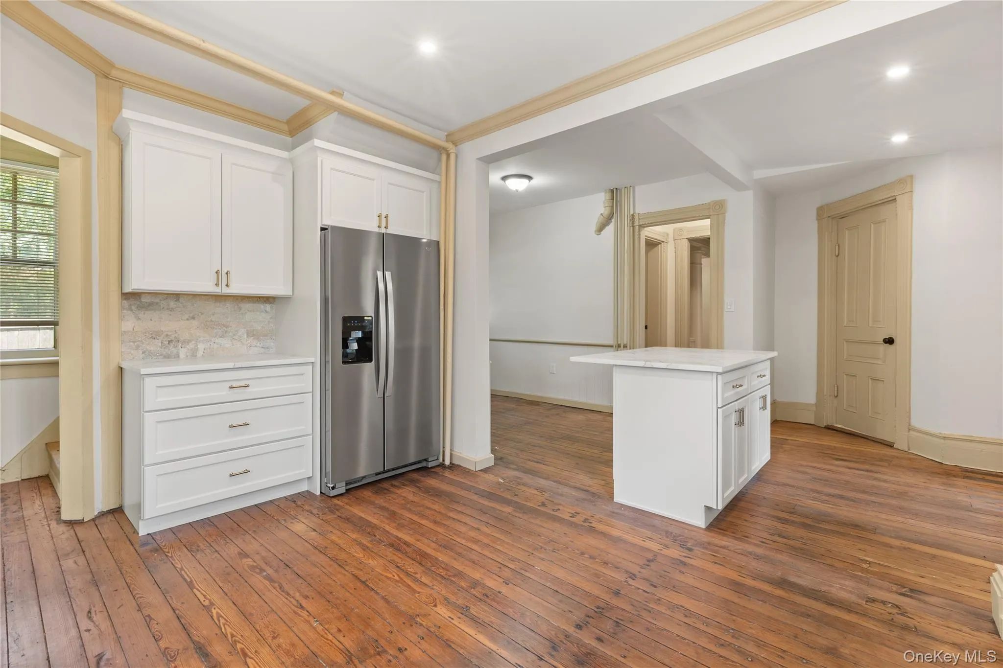 Kitchen featuring white cabinets, stainless steel refrigerator with ice dispenser, dark wood-style floors, backsplash, and recessed lighting Kitchen featuring white cabinets, stainless steel refrigerator with ice dispenser, dark wood-style floors, backsplash, and recessed lighting