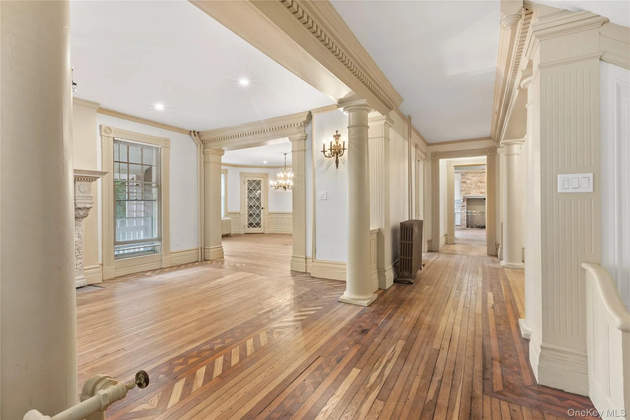 Hallway featuring hardwood / wood-style flooring, decorative columns, ornamental molding, recessed lighting, and a chandelier Hallway featuring hardwood / wood-style flooring, decorative columns, ornamental molding, recessed lighting, and a chandelier