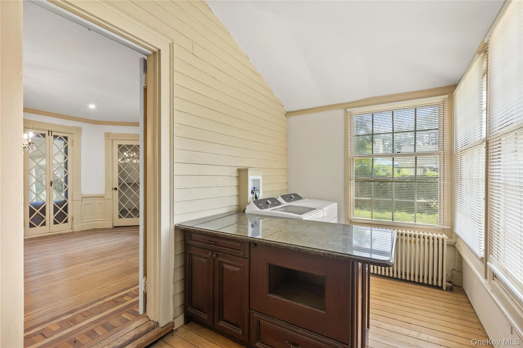 Kitchen with light wood-style flooring, radiator, dark brown cabinetry, a peninsula, and washer and clothes dryer Kitchen with light wood-style flooring, radiator, dark brown cabinetry, a peninsula, and washer and clothes dryer