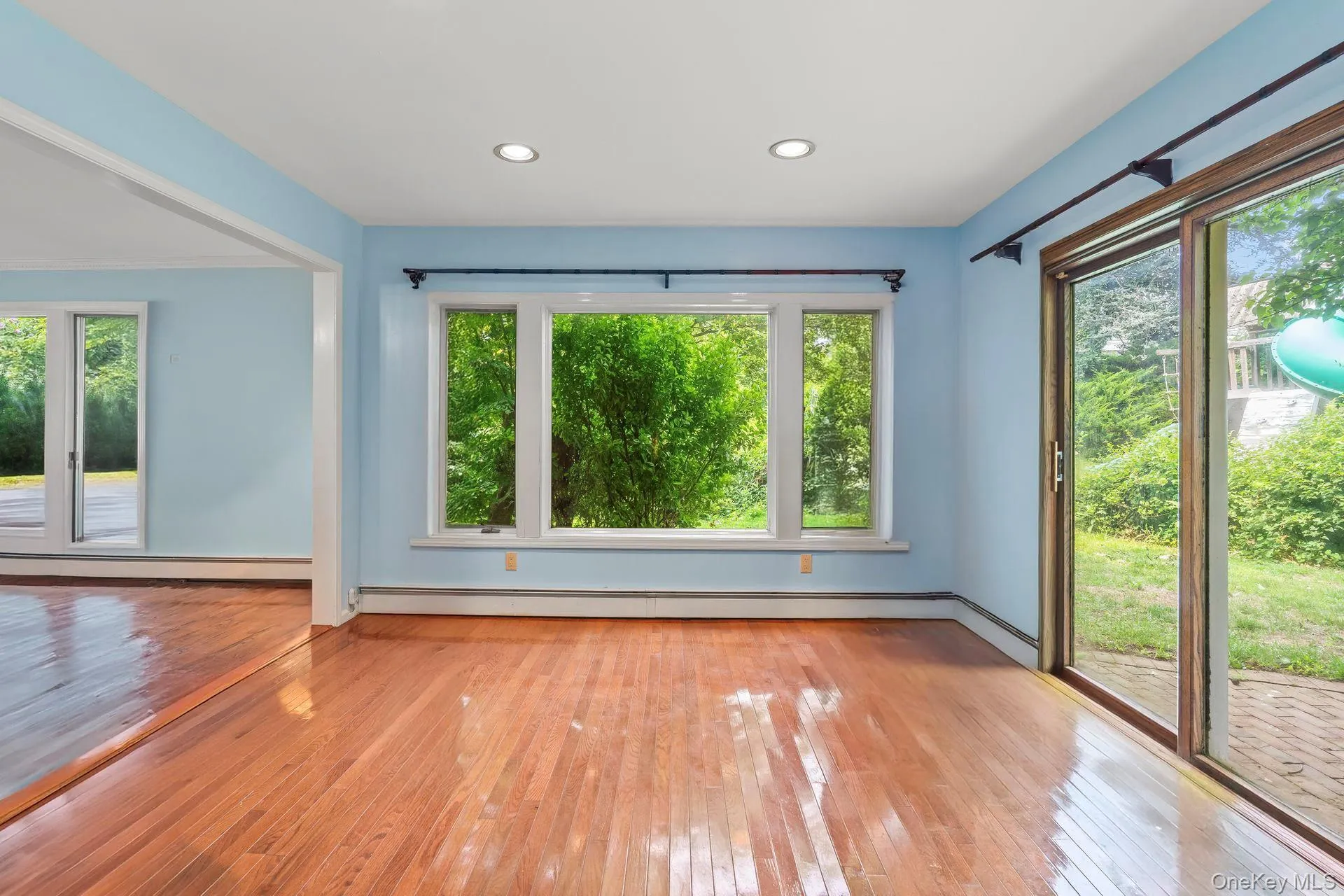 Empty room featuring wood-type flooring, a baseboard radiator, and recessed lighting Empty room featuring wood-type flooring, a baseboard radiator, and recessed lighting