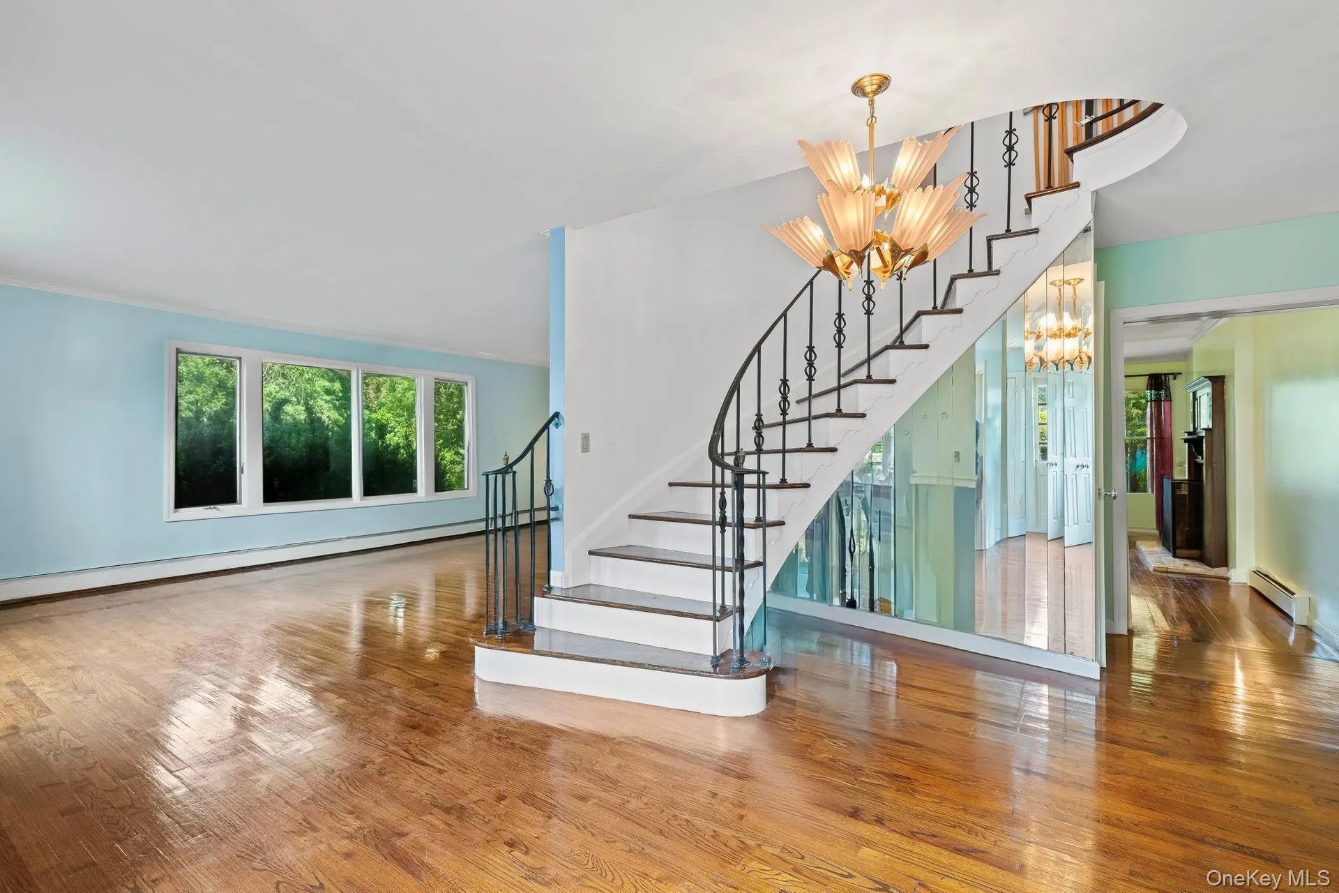 Staircase featuring hardwood / wood-style floors, a chandelier, a baseboard radiator, and a baseboard heating unit Staircase featuring hardwood / wood-style floors, a chandelier, a baseboard radiator, and a baseboard heating unit