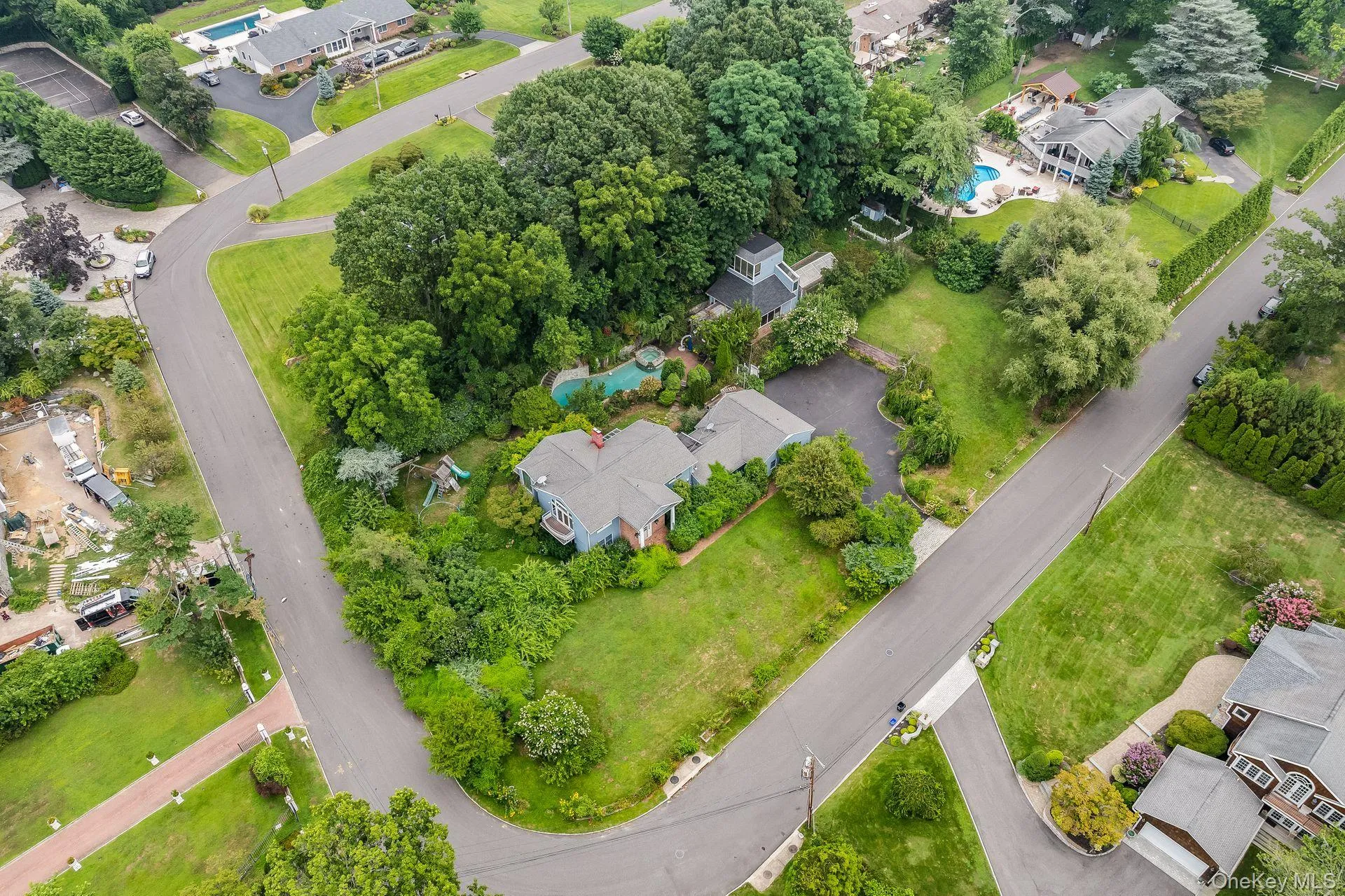 Aerial view of property and surrounding area featuring a pool area and nearby suburban area Aerial view of property and surrounding area featuring a pool area and nearby suburban area