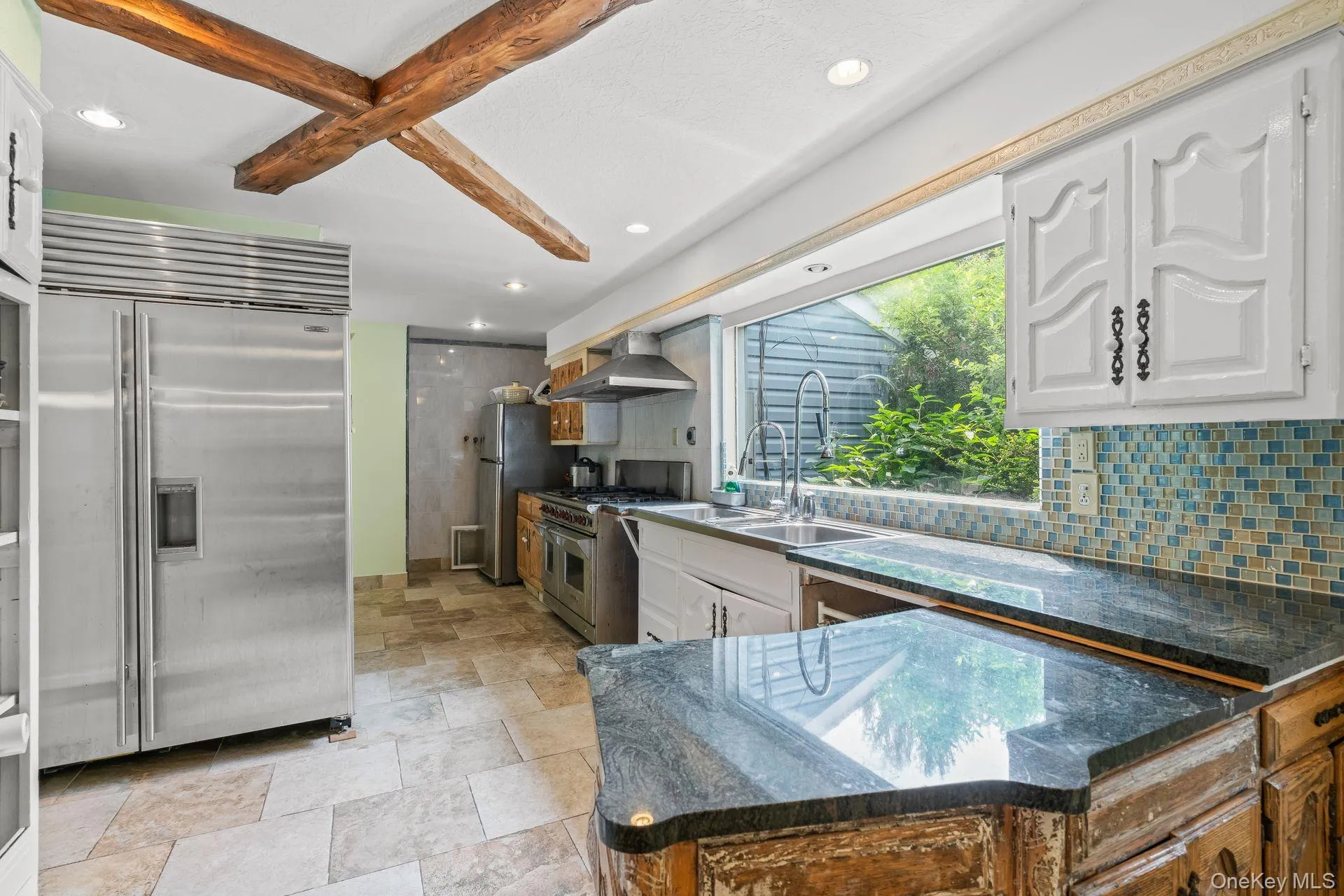 Kitchen with premium appliances, decorative backsplash, dark stone countertops, recessed lighting, and white cabinets Kitchen with premium appliances, decorative backsplash, dark stone countertops, recessed lighting, and white cabinets