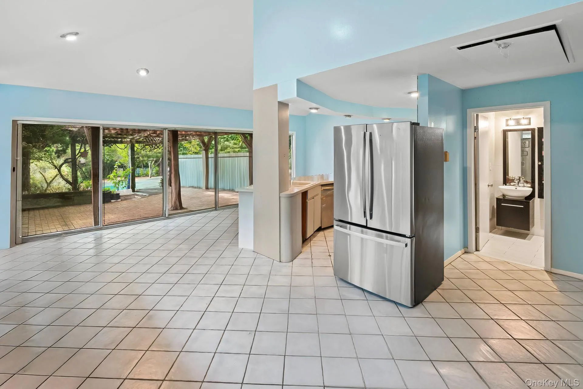 Kitchen with appliances with stainless steel finishes, light tile patterned flooring, vaulted ceiling, recessed lighting, and light countertops Kitchen with appliances with stainless steel finishes, light tile patterned flooring, vaulted ceiling, recessed lighting, and light countertops