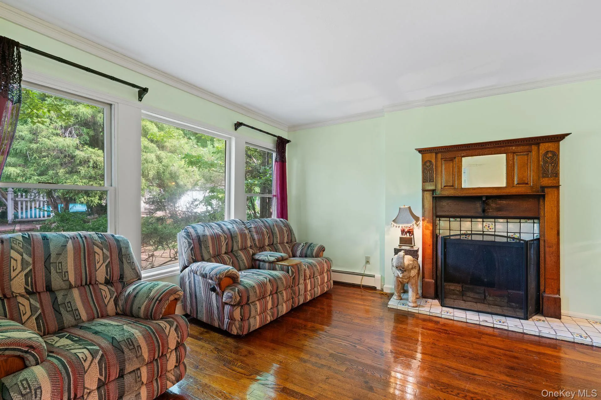 Living area with dark wood-style floors, crown molding, a fireplace, and baseboard heating Living area with dark wood-style floors, crown molding, a fireplace, and baseboard heating