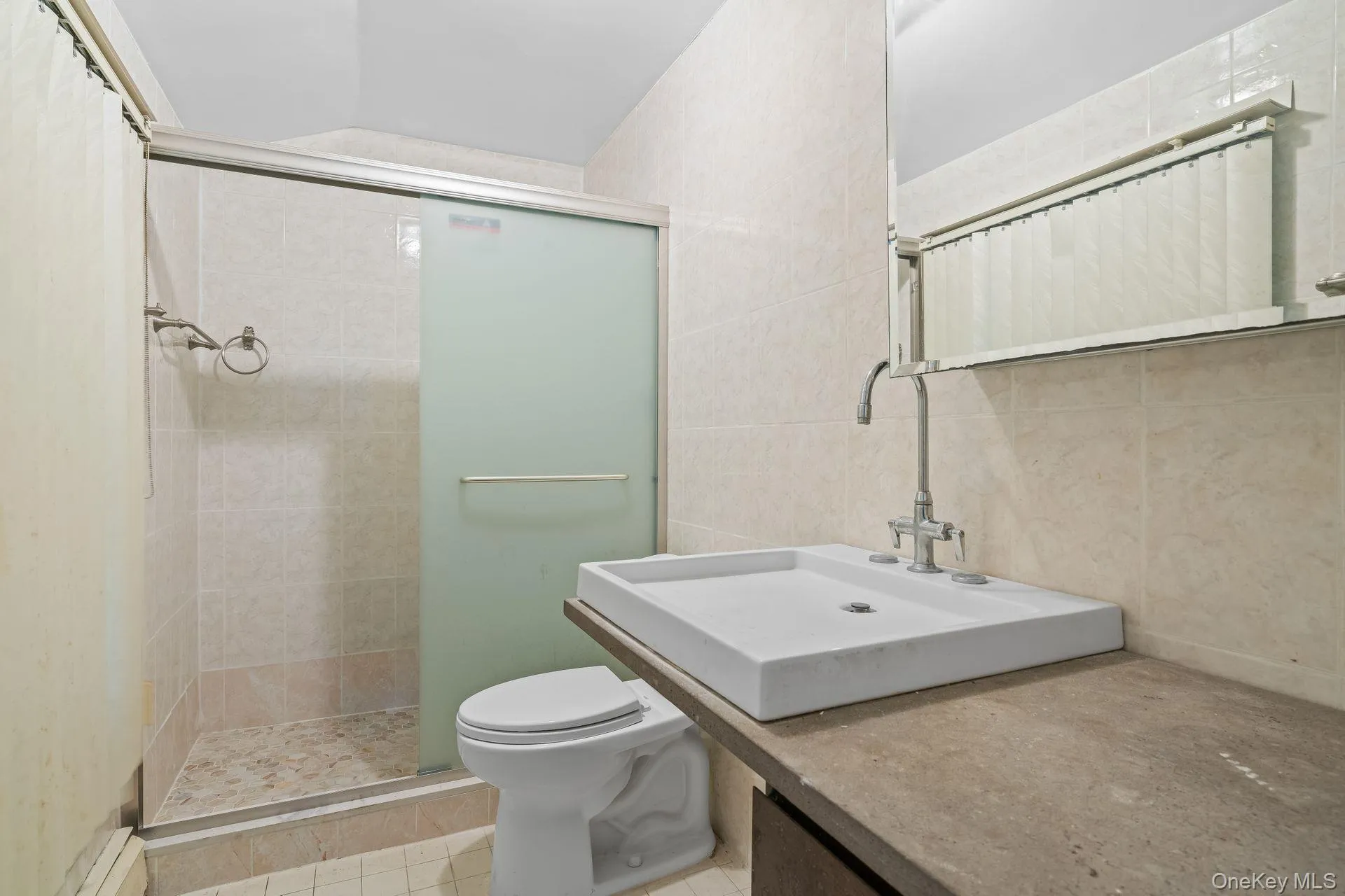 Full bathroom with a stall shower, tile walls, vanity, and light tile patterned floors Full bathroom with a stall shower, tile walls, vanity, and light tile patterned floors