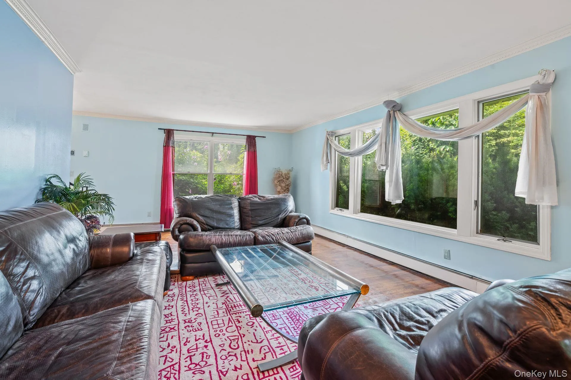 Living area with a baseboard radiator, crown molding, and wood finished floors Living area with a baseboard radiator, crown molding, and wood finished floors