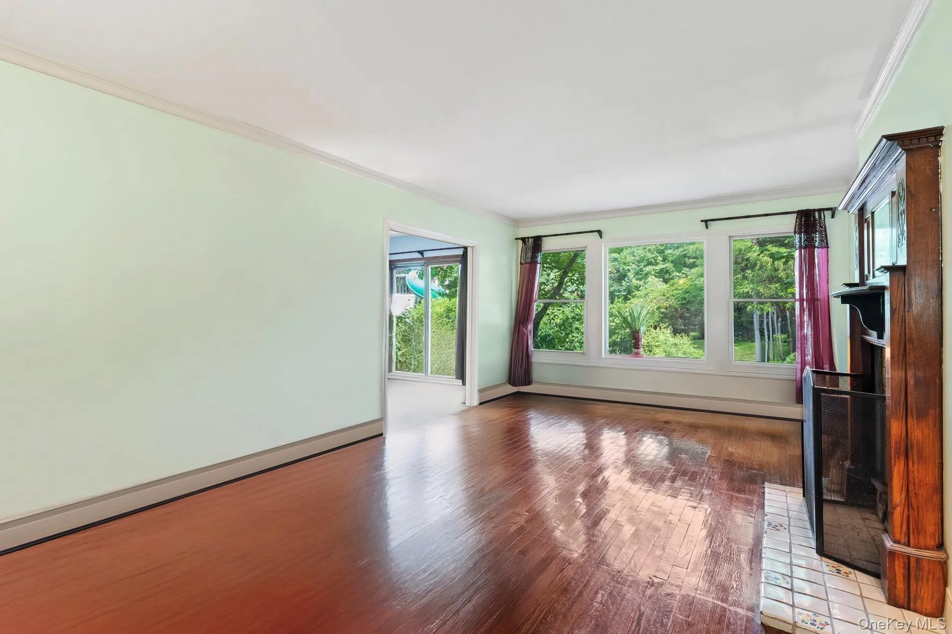 Unfurnished living room featuring ornamental molding, wood finished floors, and a baseboard radiator Unfurnished living room featuring ornamental molding, wood finished floors, and a baseboard radiator
