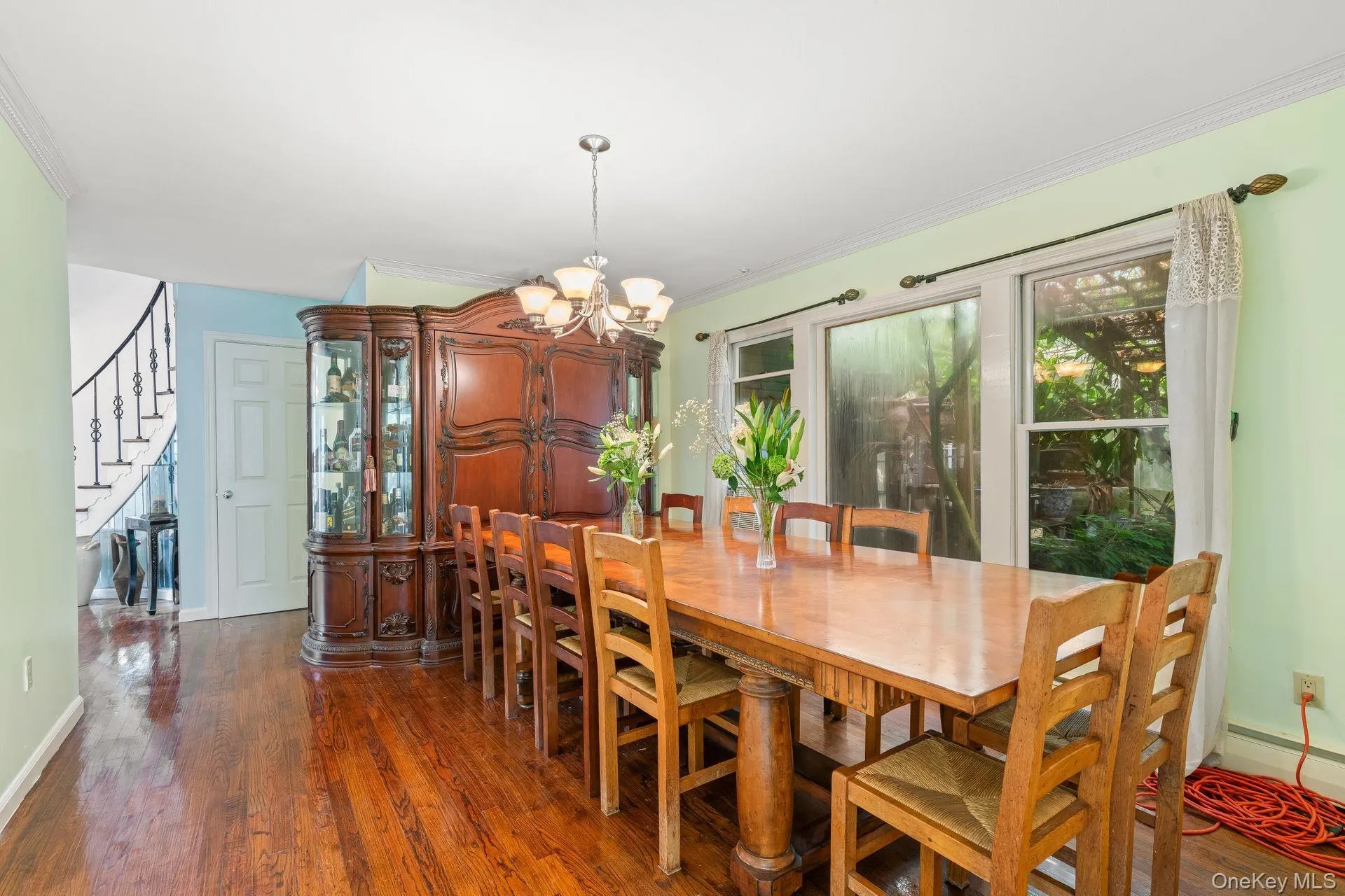 Dining room with dark wood-type flooring, a chandelier, ornamental molding, and stairway Dining room with dark wood-type flooring, a chandelier, ornamental molding, and stairway