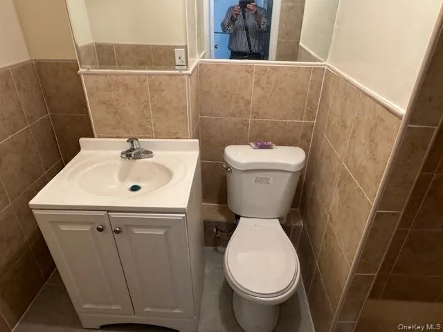 Bathroom featuring tile walls, vanity, a wainscoted wall, and a tile shower Bathroom featuring tile walls, vanity, a wainscoted wall, and a tile shower