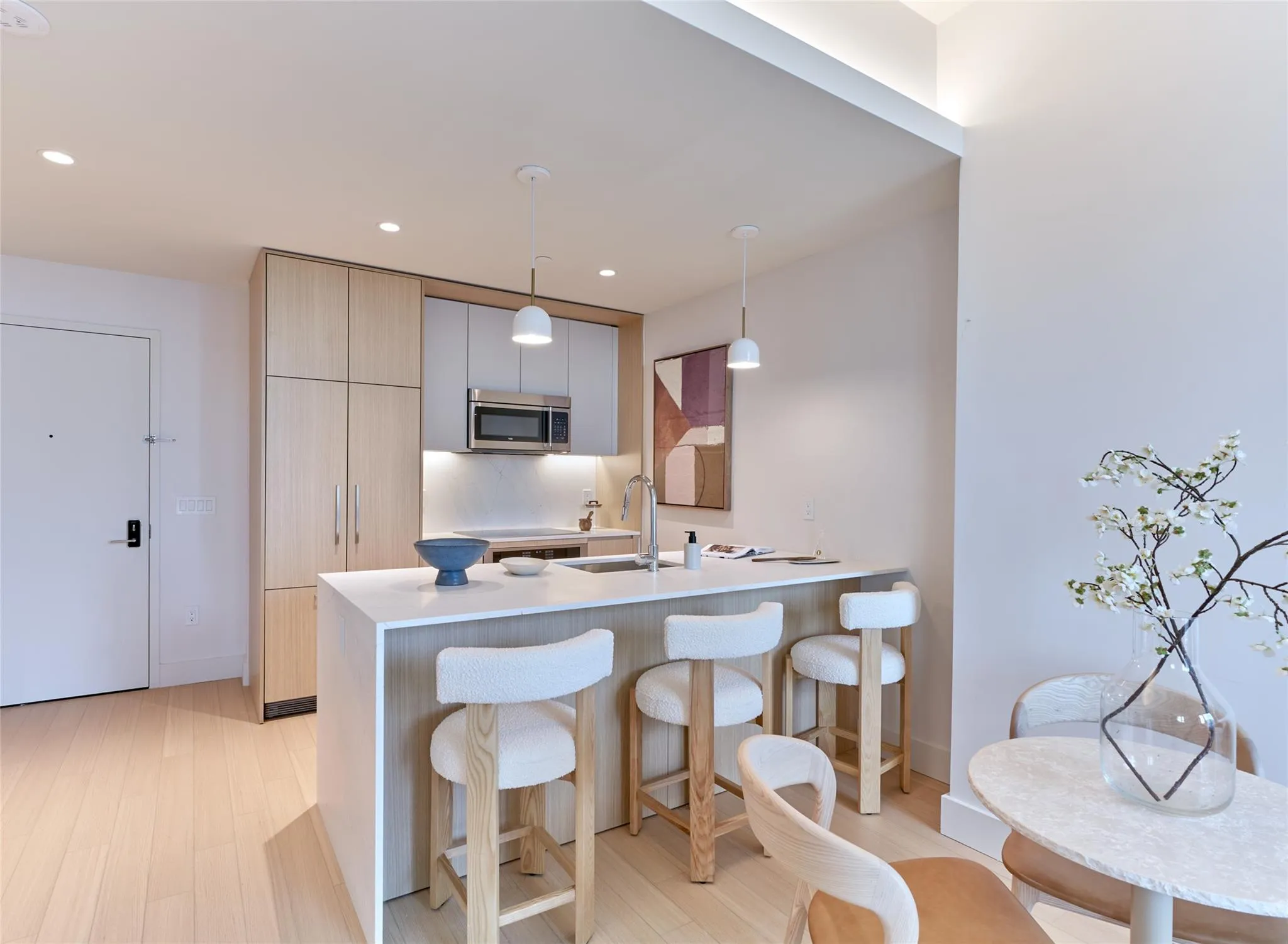 Kitchen with modern cabinets, a peninsula, a breakfast bar, stainless steel microwave, and decorative light fixtures Kitchen with modern cabinets, a peninsula, a breakfast bar, stainless steel microwave, and decorative light fixtures