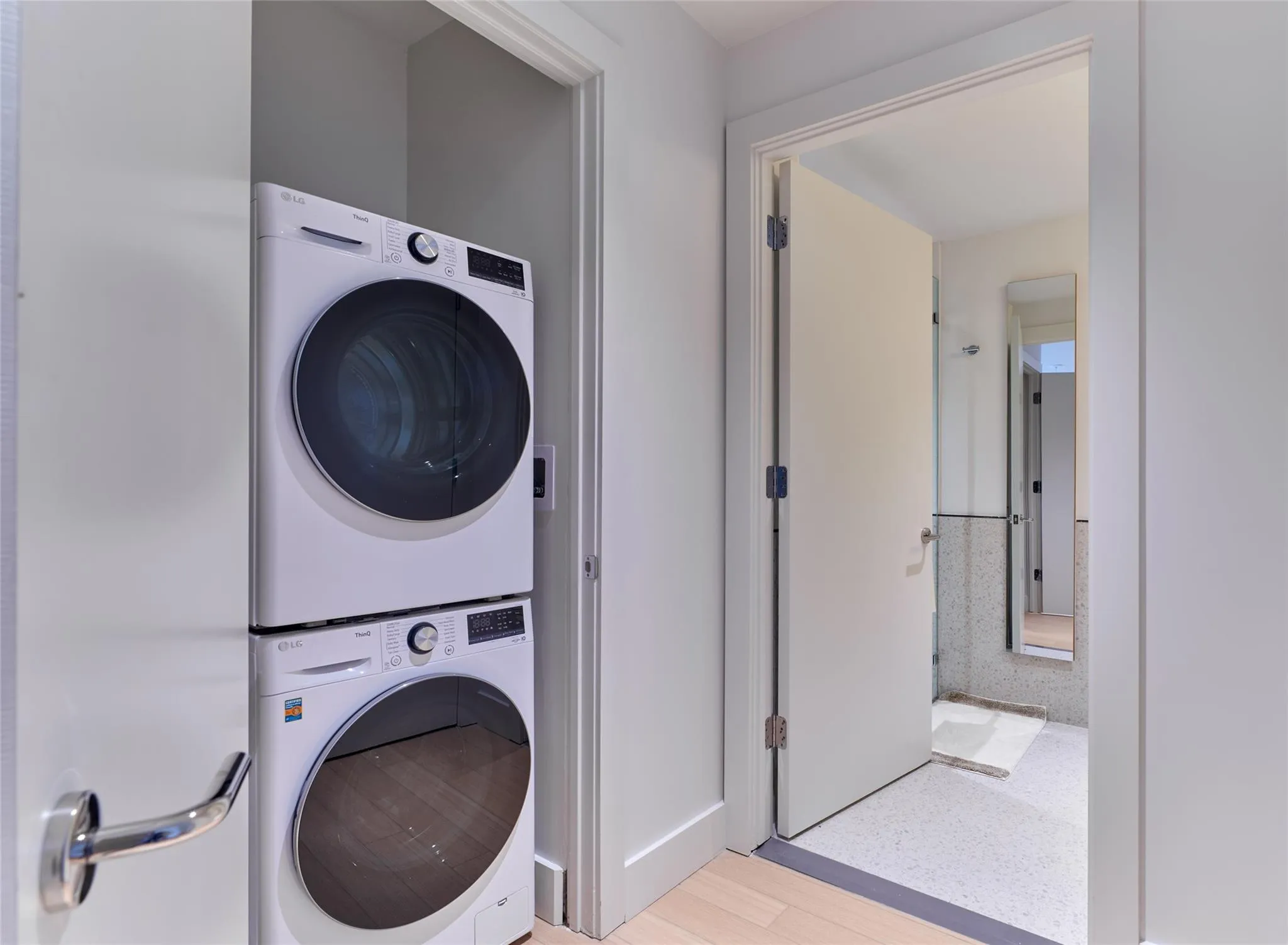 Laundry area with stacked washer / dryer and light wood-style flooring Laundry area with stacked washer / dryer and light wood-style flooring