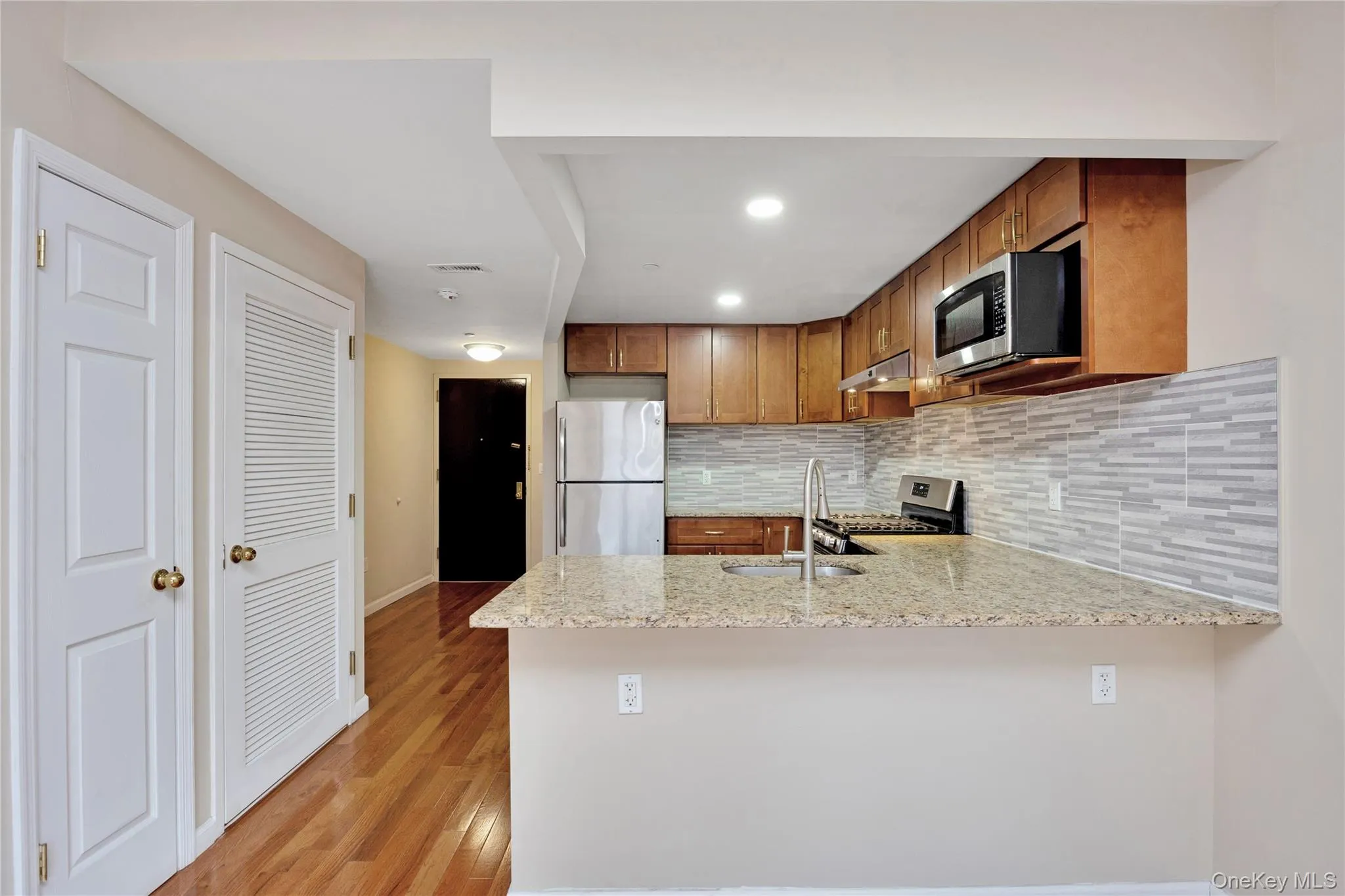 Kitchen with a peninsula, under cabinet range hood, brown cabinets, stainless steel appliances, and a sink Kitchen with a peninsula, under cabinet range hood, brown cabinets, stainless steel appliances, and a sink
