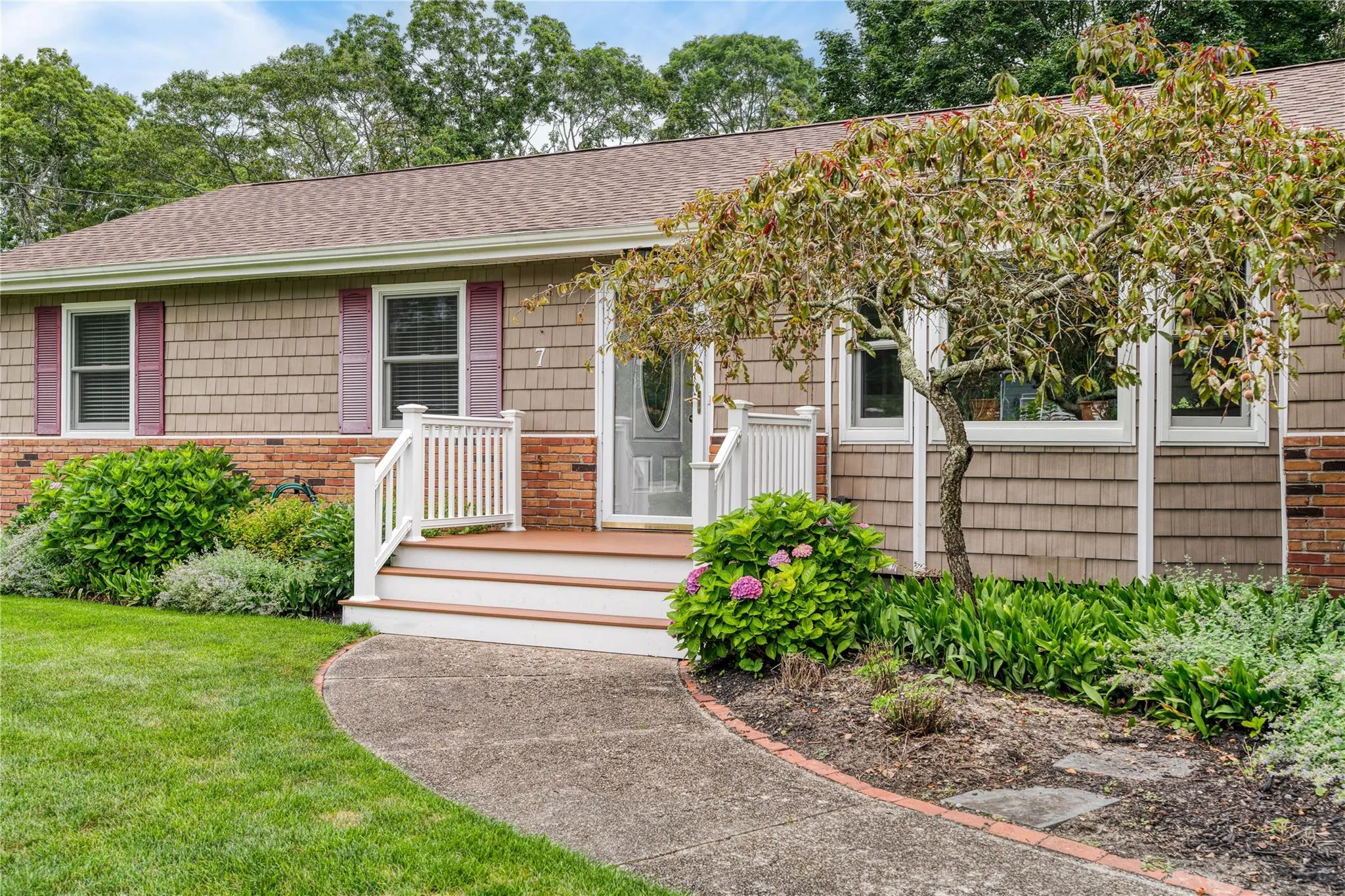 View of front of house with roof with shingles, a front yard, and brick siding