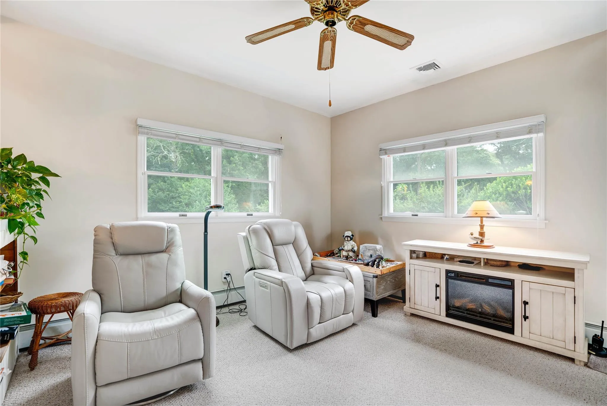 Living area with a ceiling fan, baseboard heating, and light colored carpet