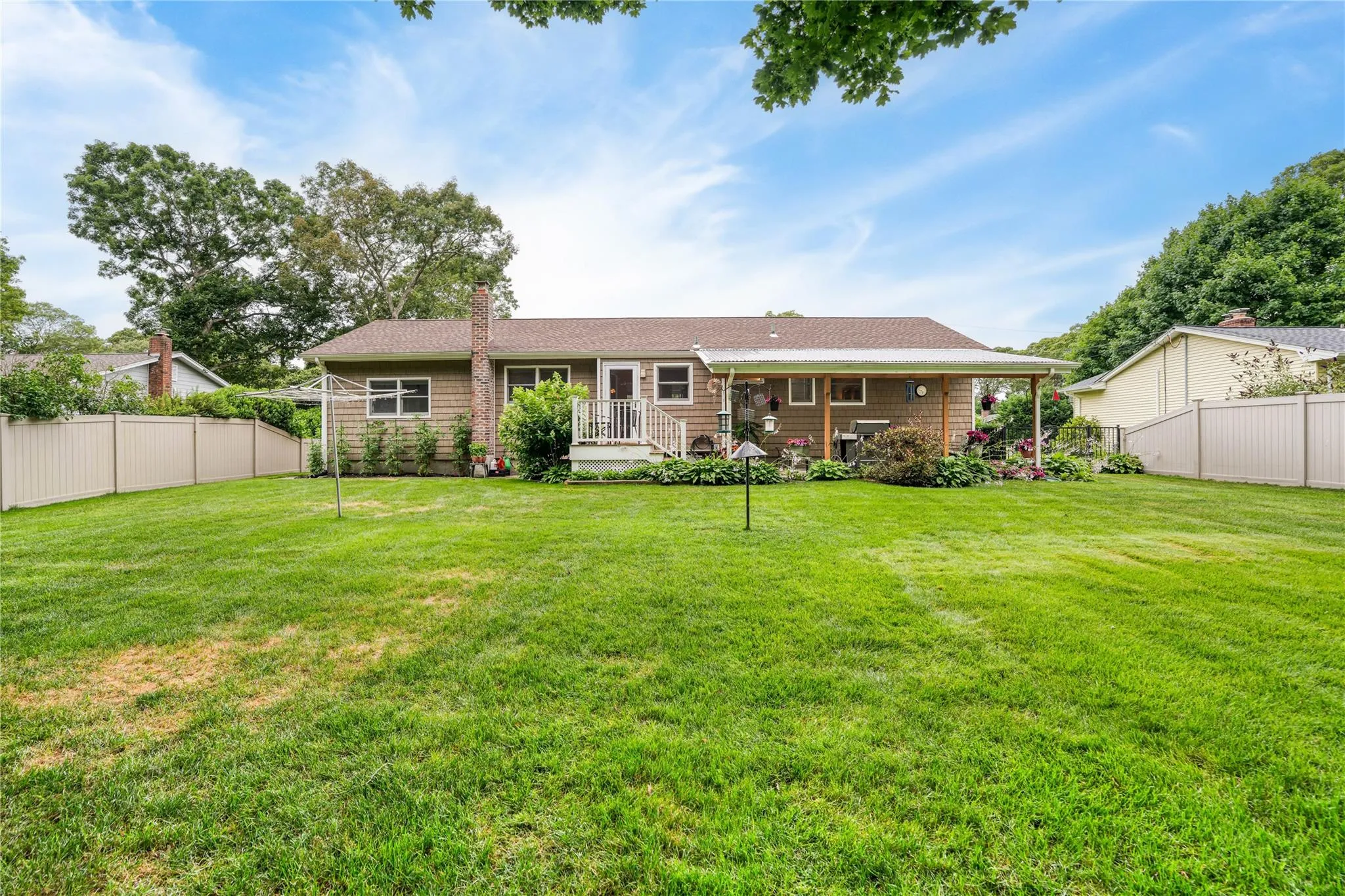 Back of house featuring a fenced backyard, a chimney, a wooden deck, and a shingled roof