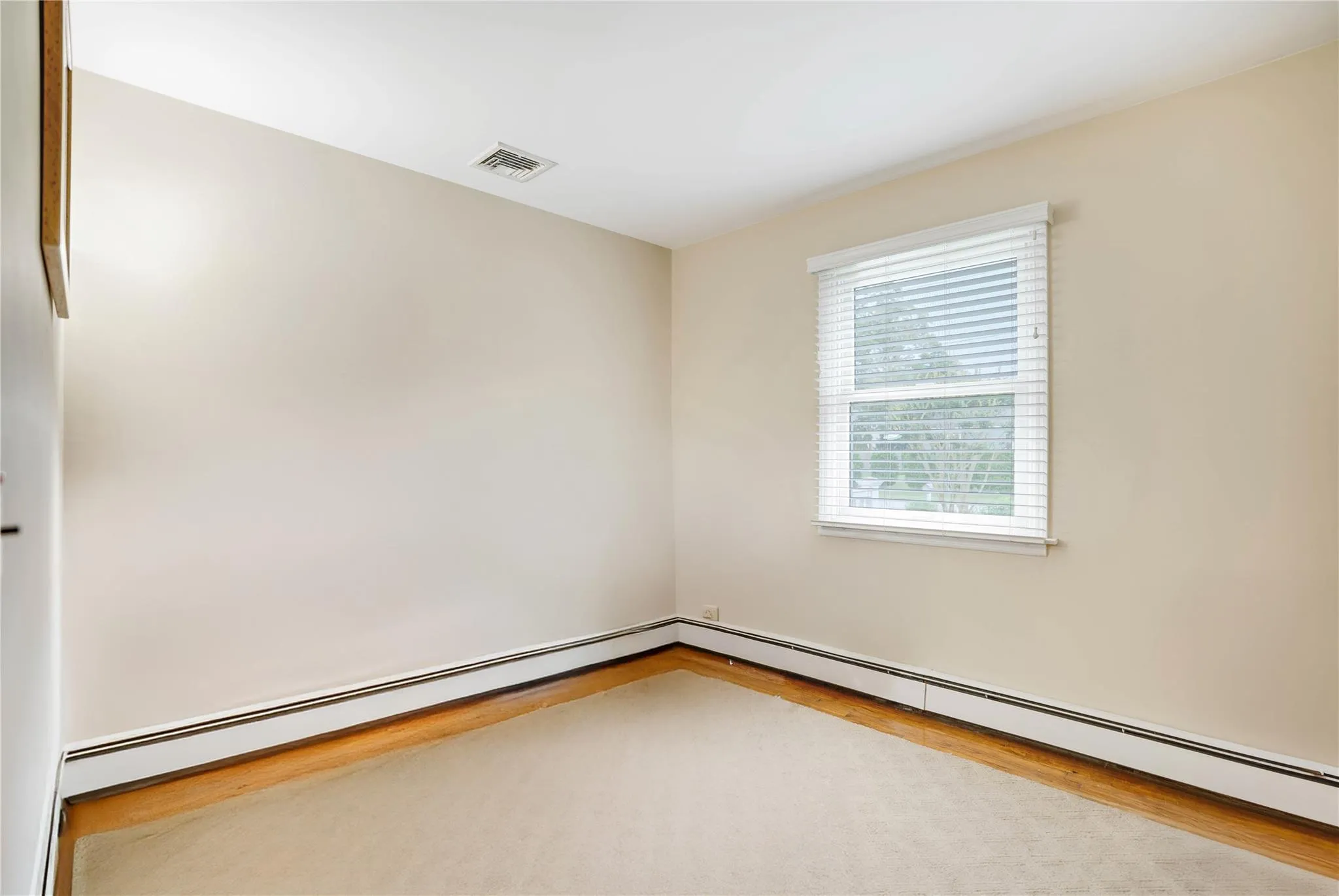 Empty room featuring a baseboard radiator and wood finished floors